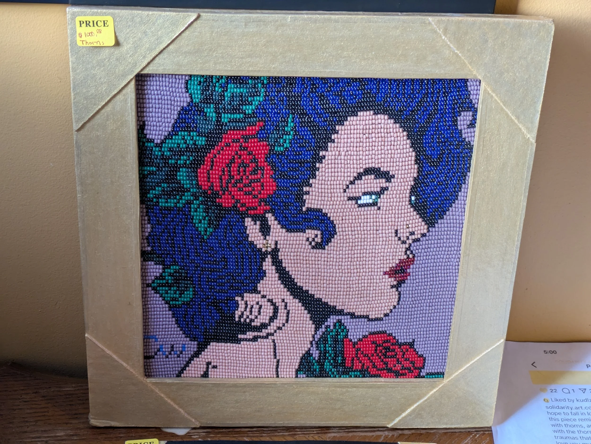 Beadwork of a white woman in profile with black hair and a red rose tucked behind her ear