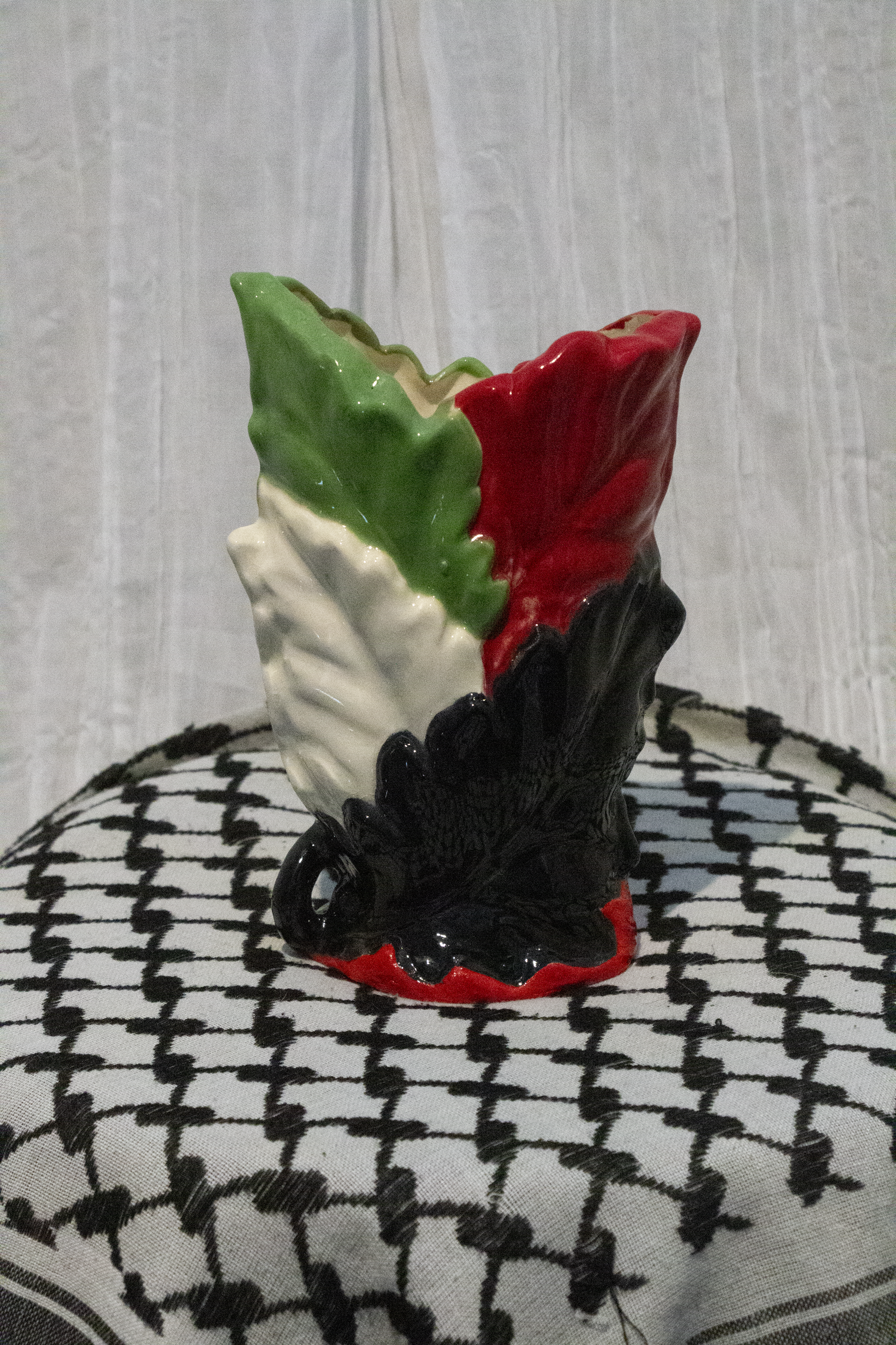 "Vase 6", a small ceramic vase of leaves painted in green, black, and red to represent the Palestinian flag