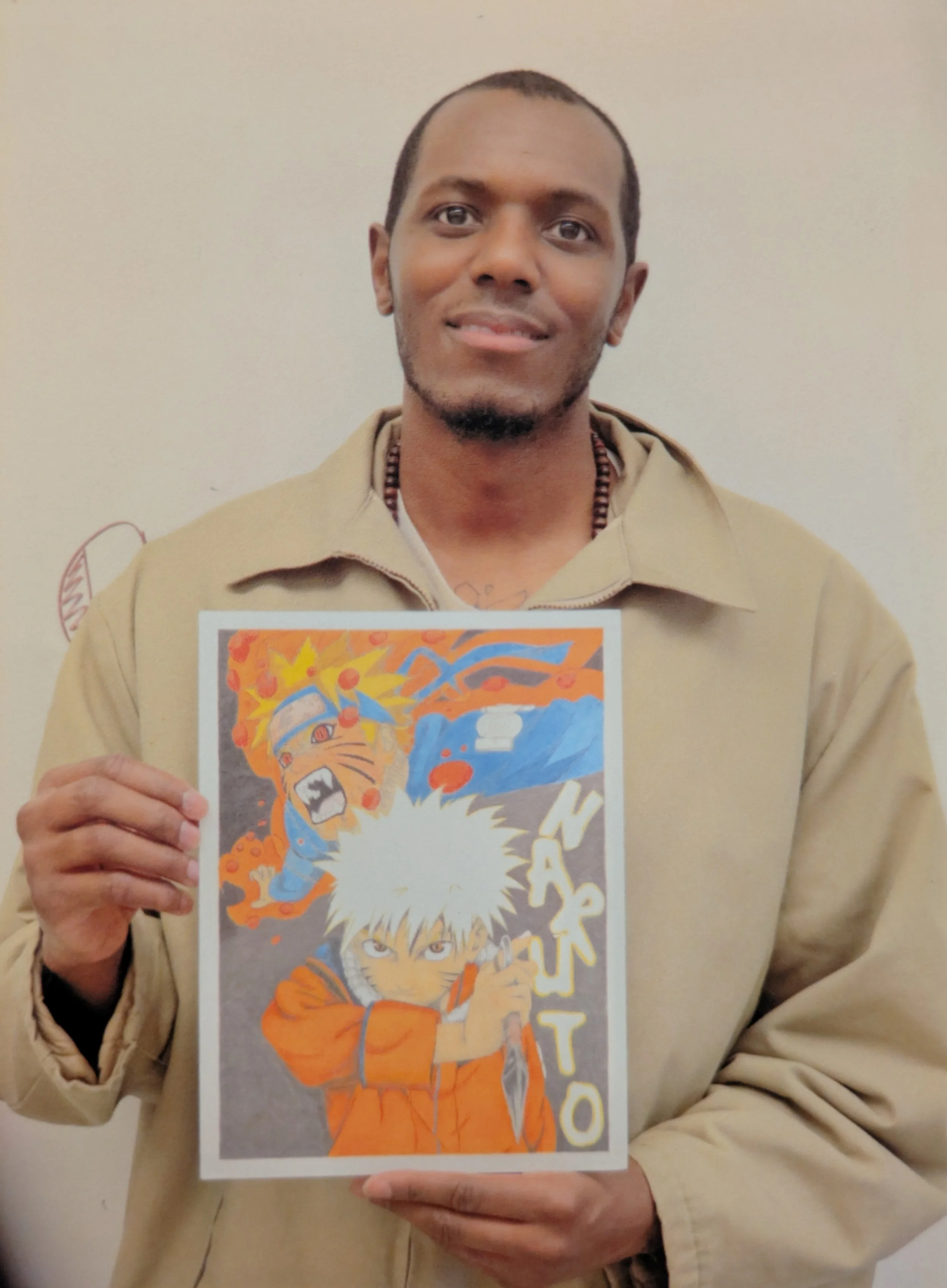 Photo of a man holding a piece of Naruto artwork