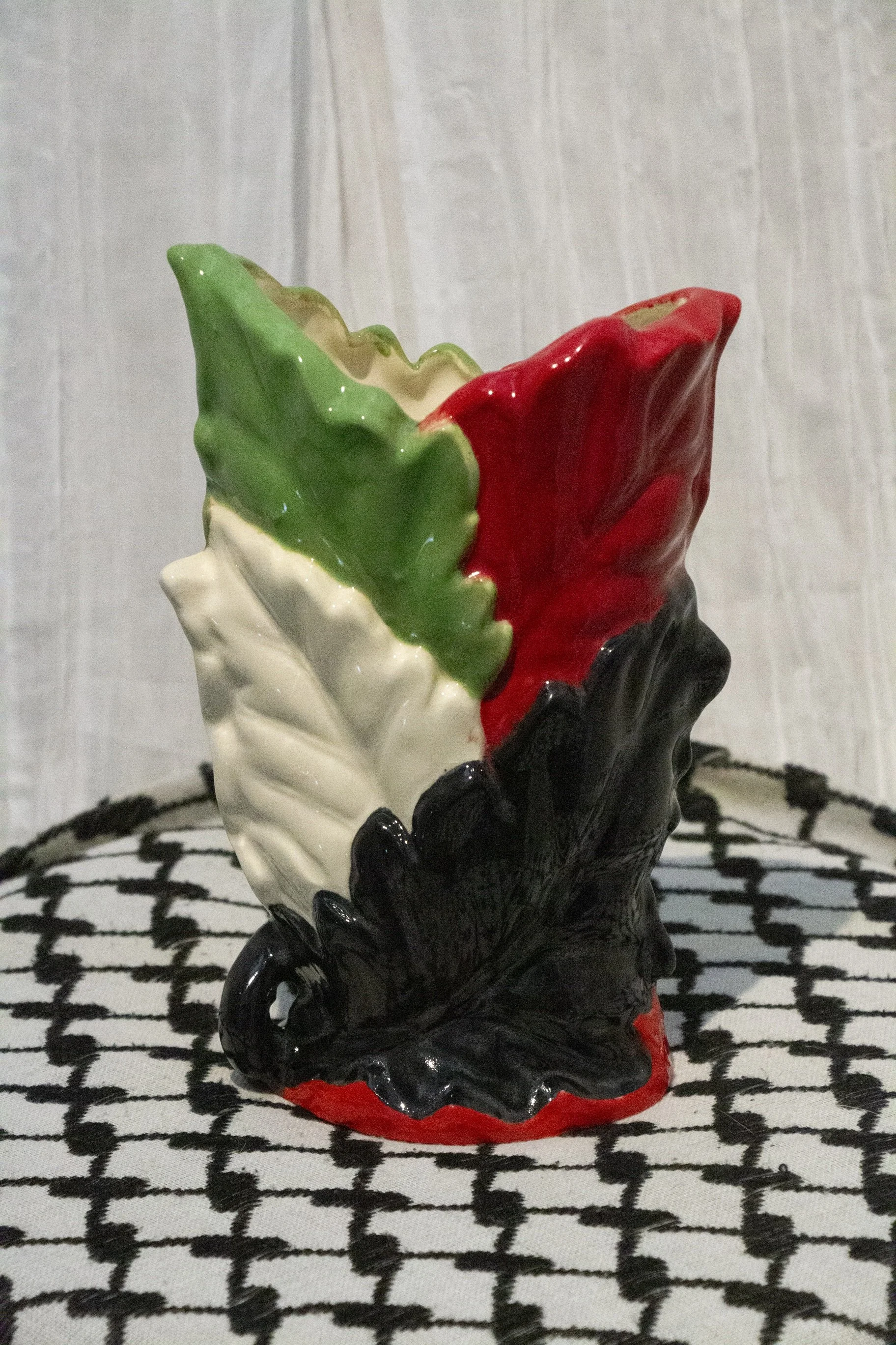 "Vase 4", a small ceramic vase of leaves painted in green, black, and red to represent the Palestinian flag