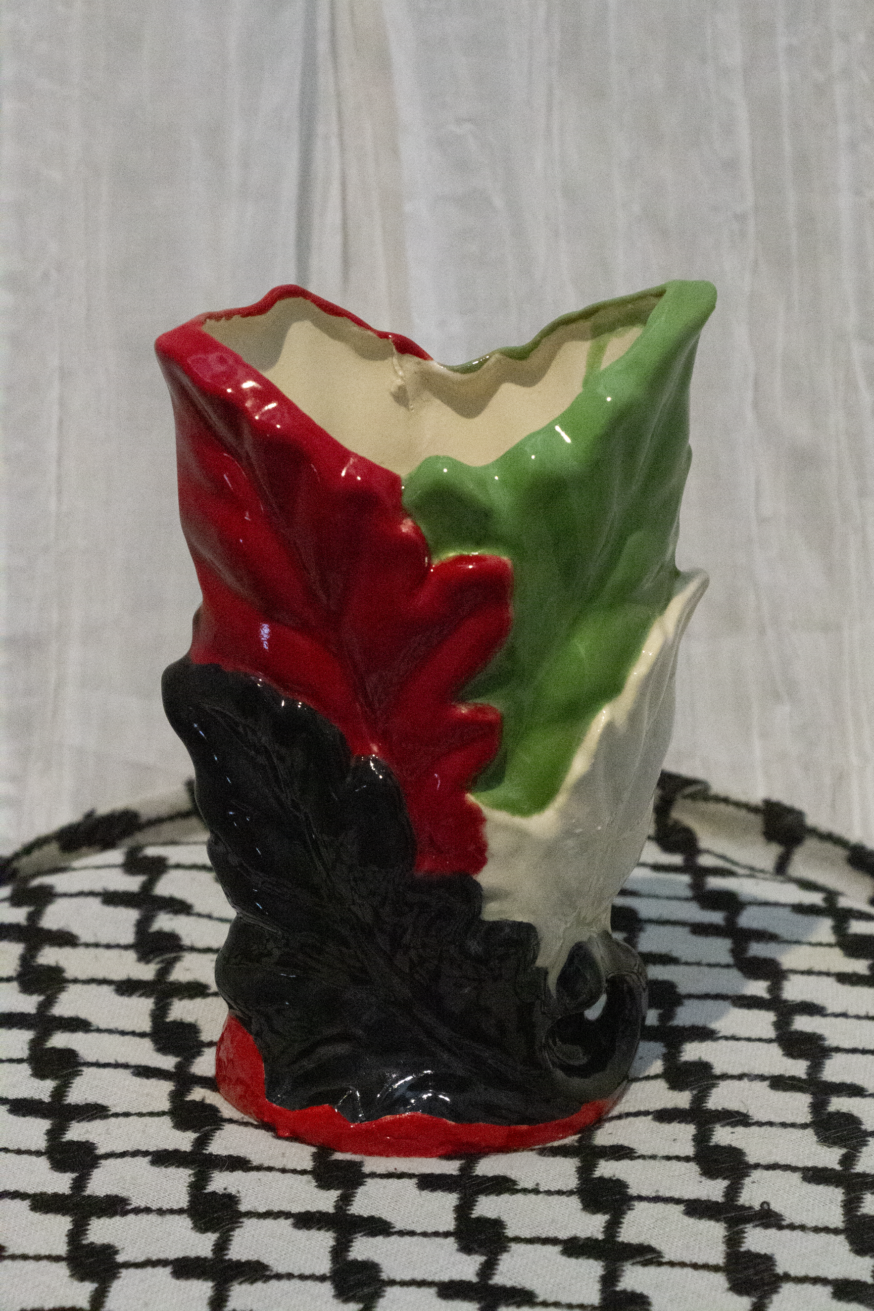 "Vase 2", a small ceramic vase of leaves painted in green, black, and red to represent the Palestinian flag