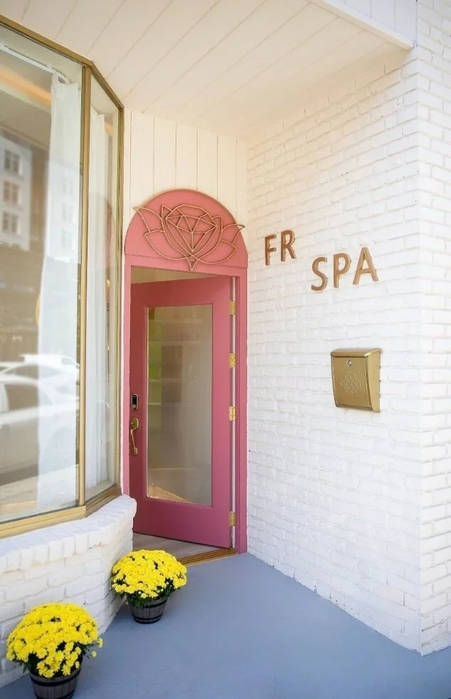 A business store front with FR SPA written on the wall in gold. A pink door leads into the building.