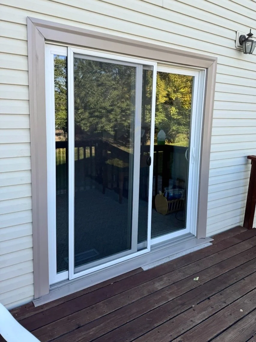 Sliding glass door on a deck with white siding and outdoor light fixture