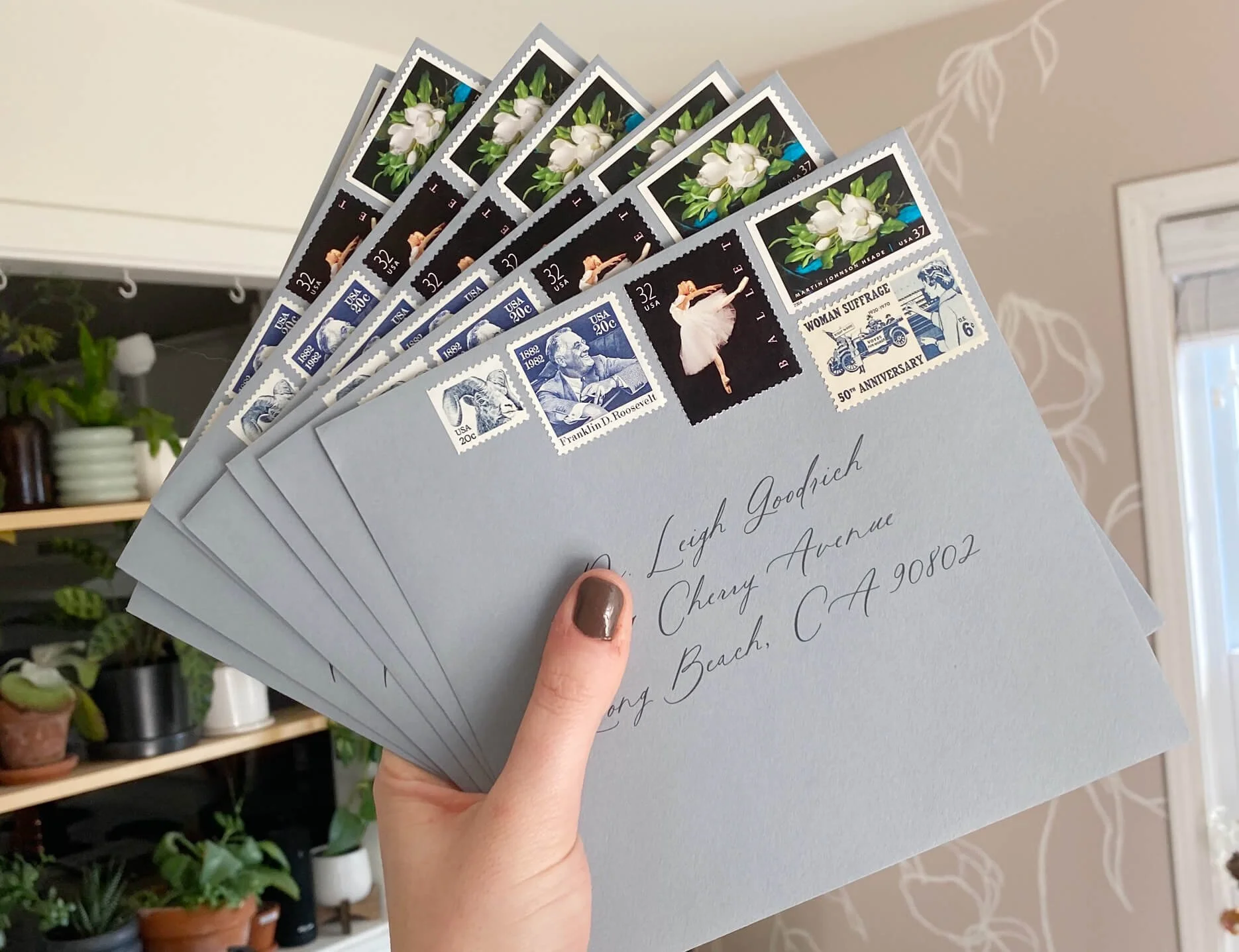 holding envelopes for wedding invitations with curated vintage stamps on them