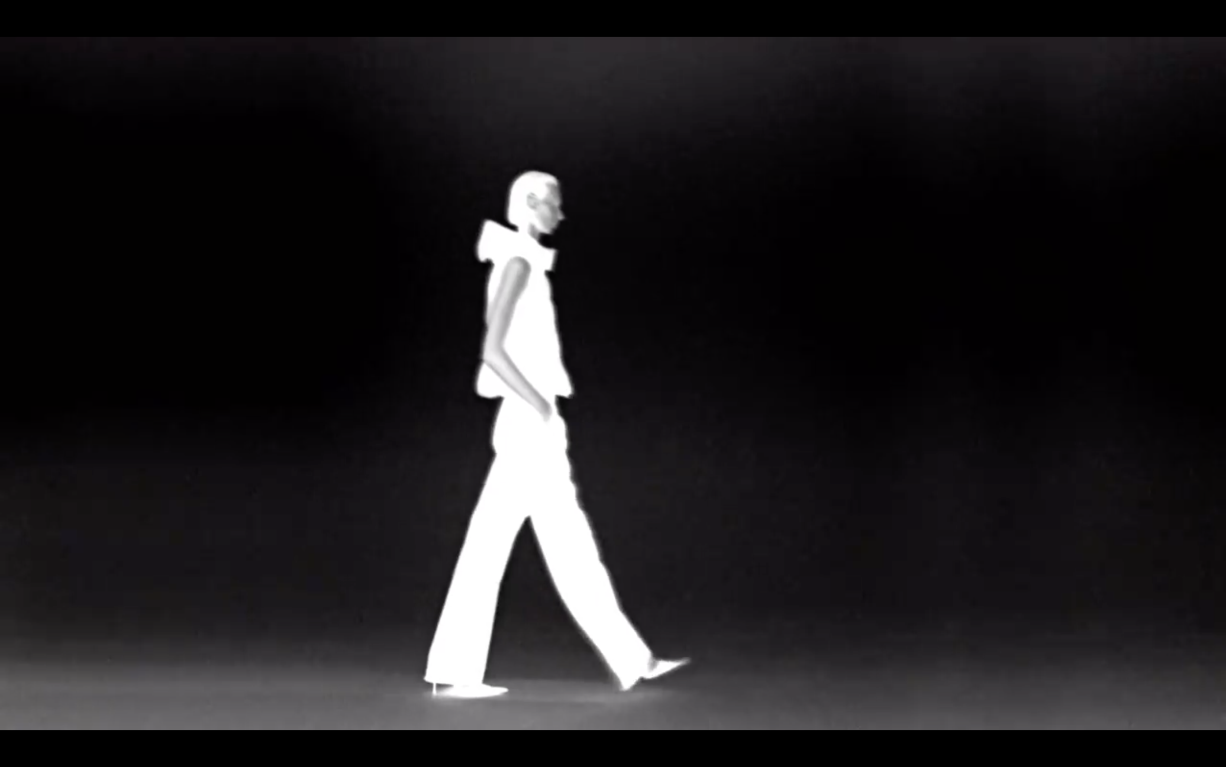 Image en noir et blanc d'une silhouette humaine marchant de profil sur un fond sombre.