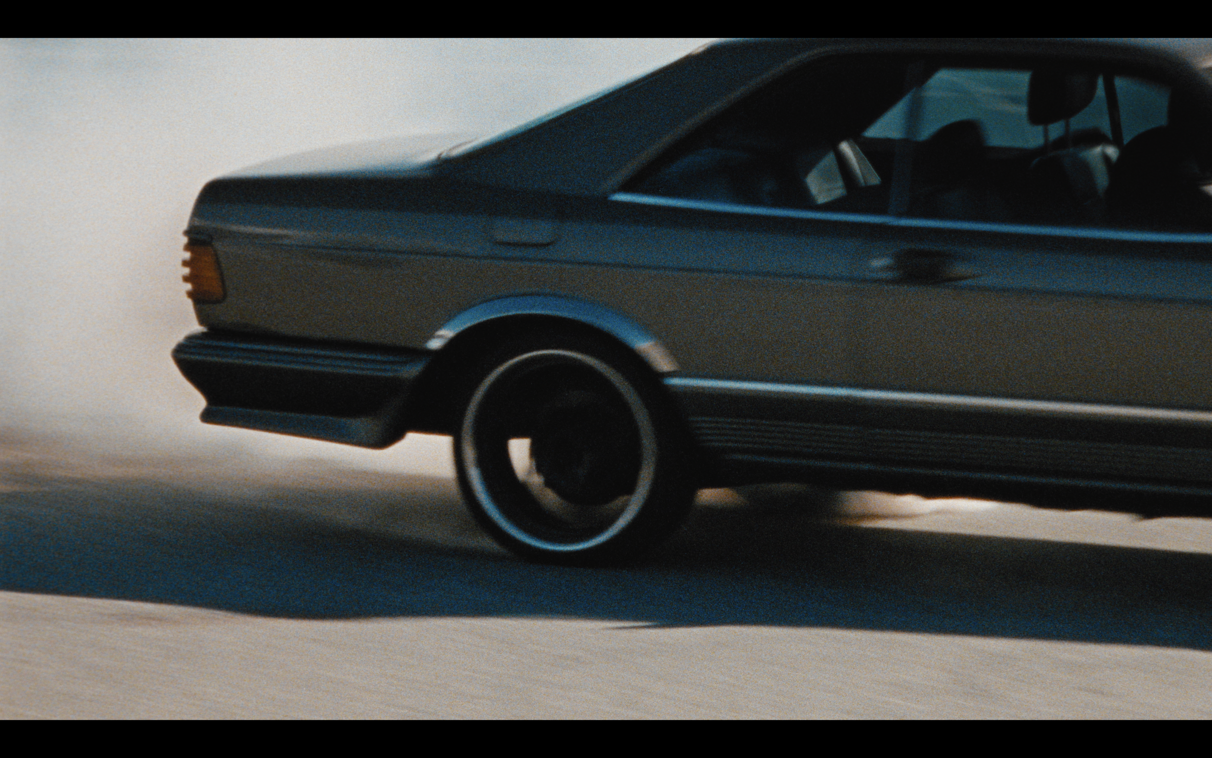 Voiture classique en train de déraper avec de la fumée sortant des roues arrières.