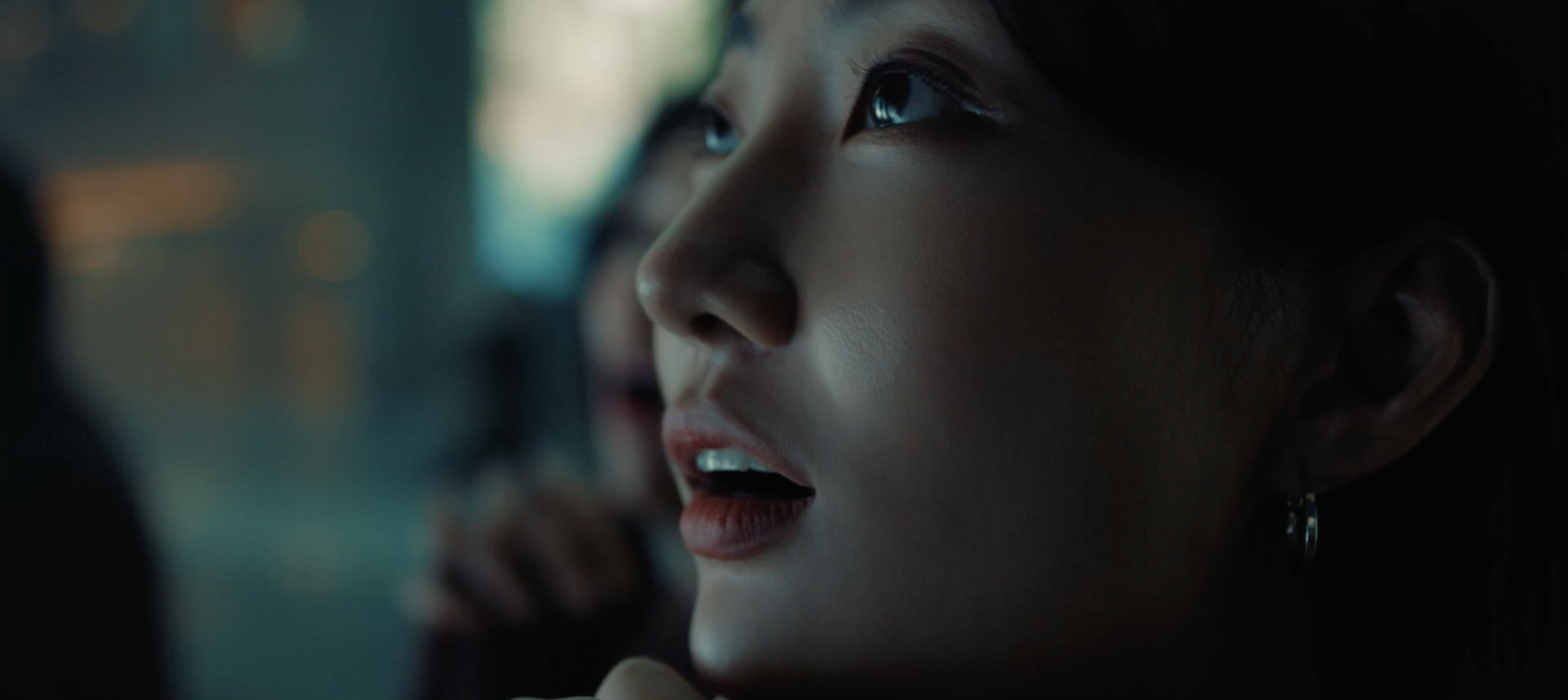 Gros plan sur le visage d'une femme regardant vers le haut d'un air captivé, illuminé par une lumière douce.