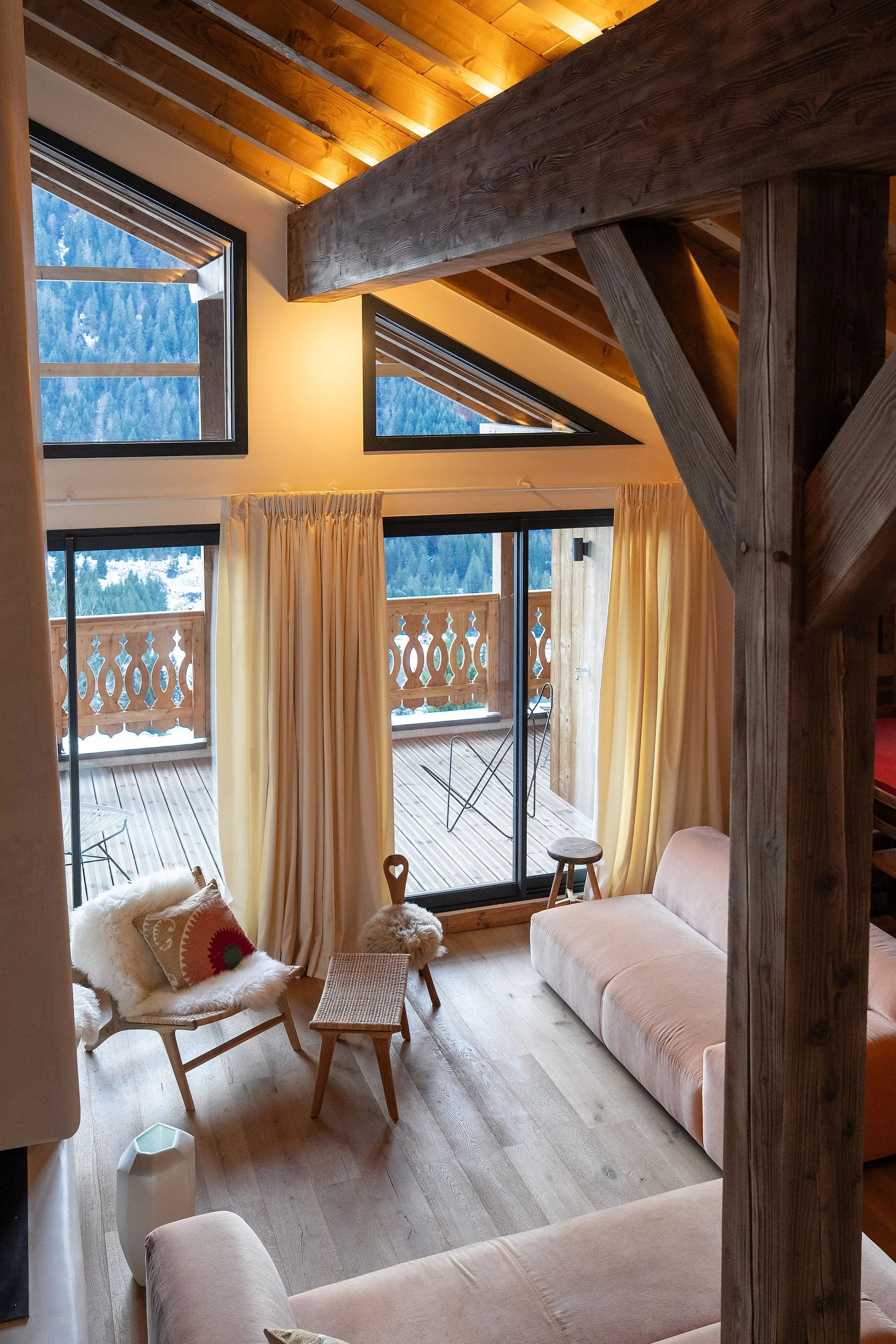 Salon intérieur d'une maison en bois avec grandes fenêtres et balcon en bois, matériel responsable d'une maison de montagne avec vue sur la forêt enneigée.