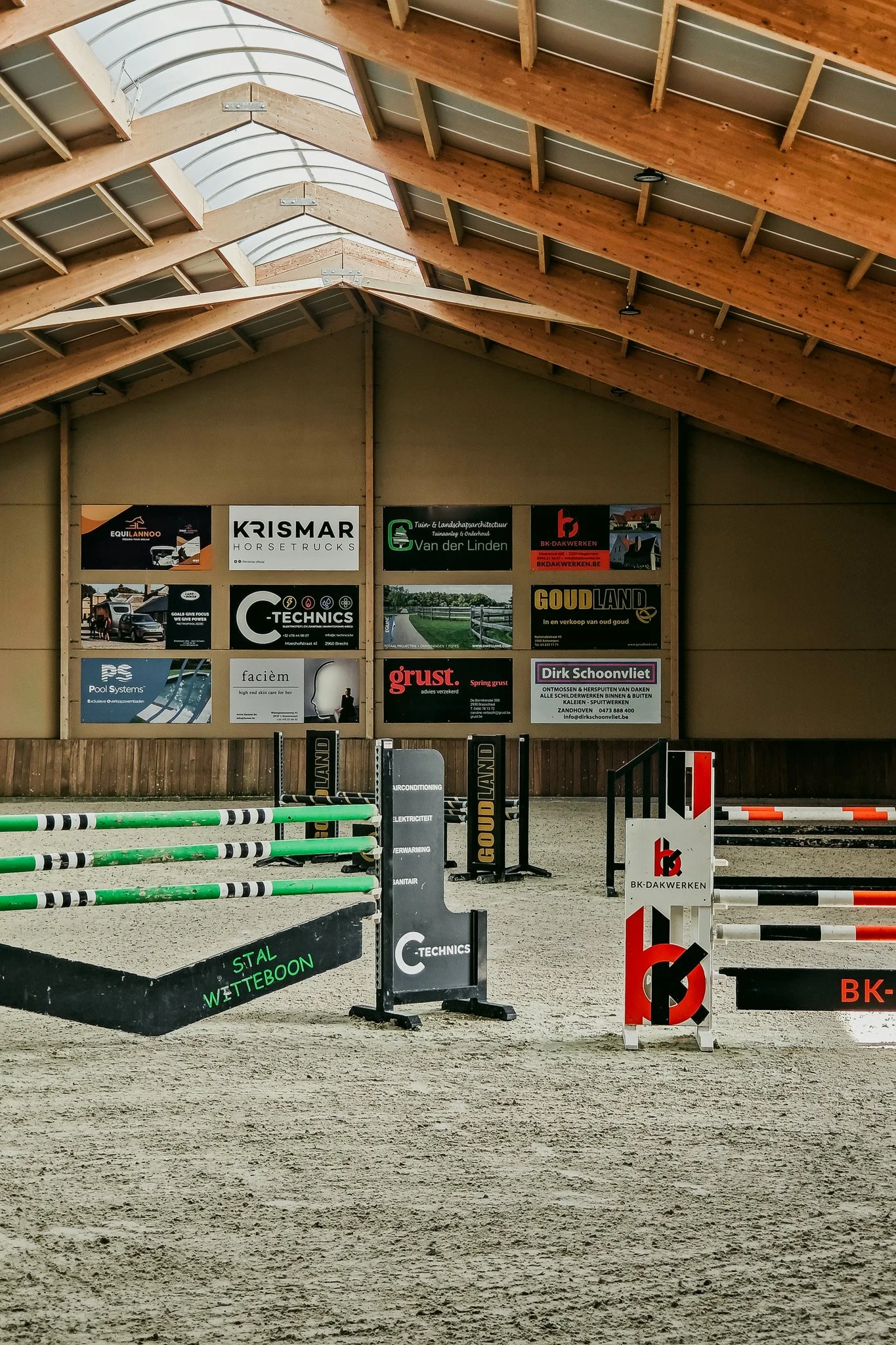 Overdekte manege met springhindernissen in een paardrijhal.