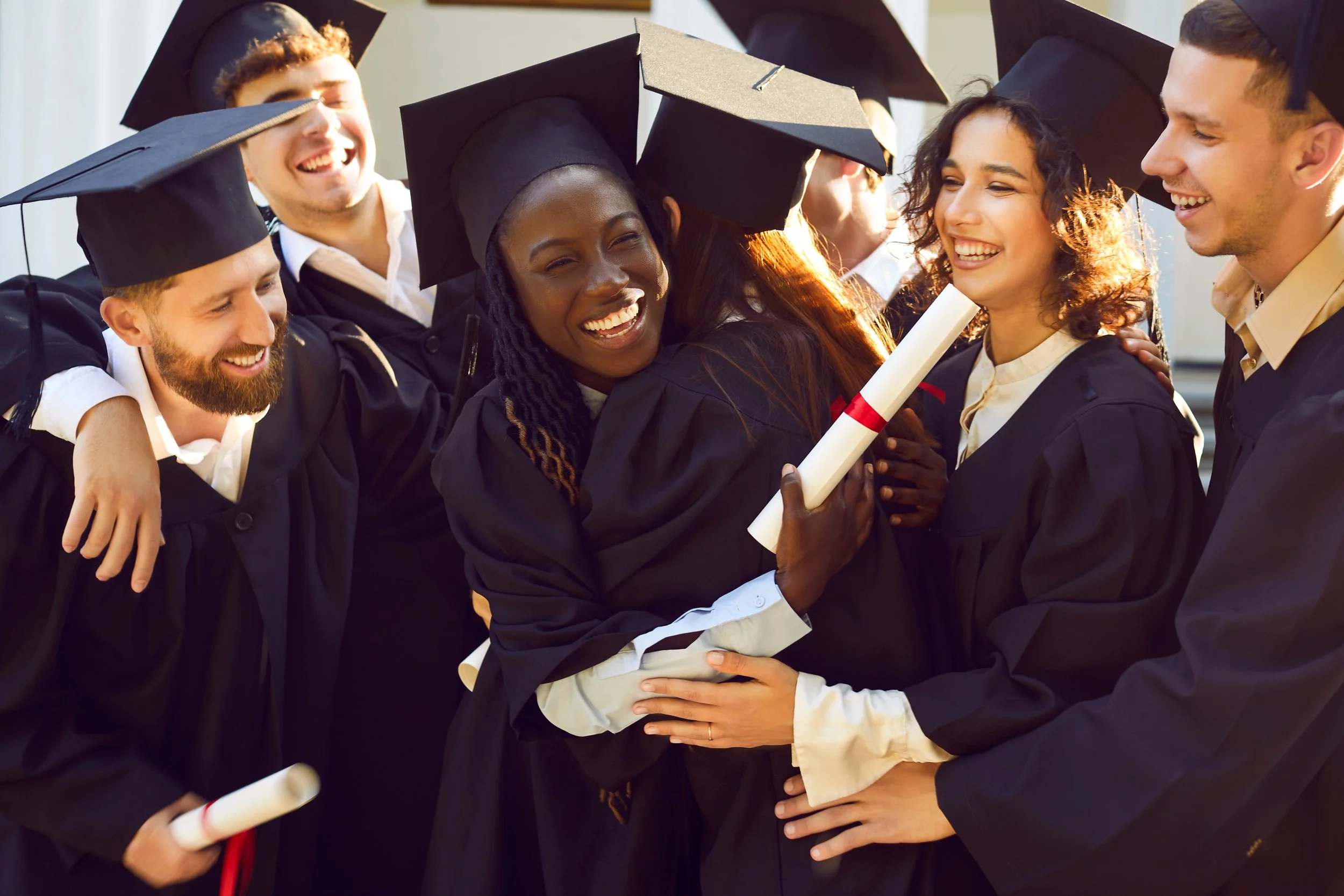 A group of young graduates celebrating in their caps and gowns.