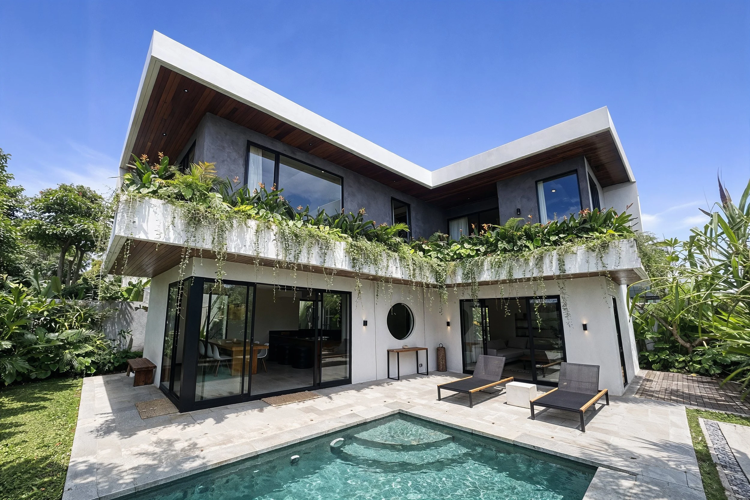 Modern two-story house with large windows, a balcony, and a backyard with a swimming pool, surrounded by greenery.