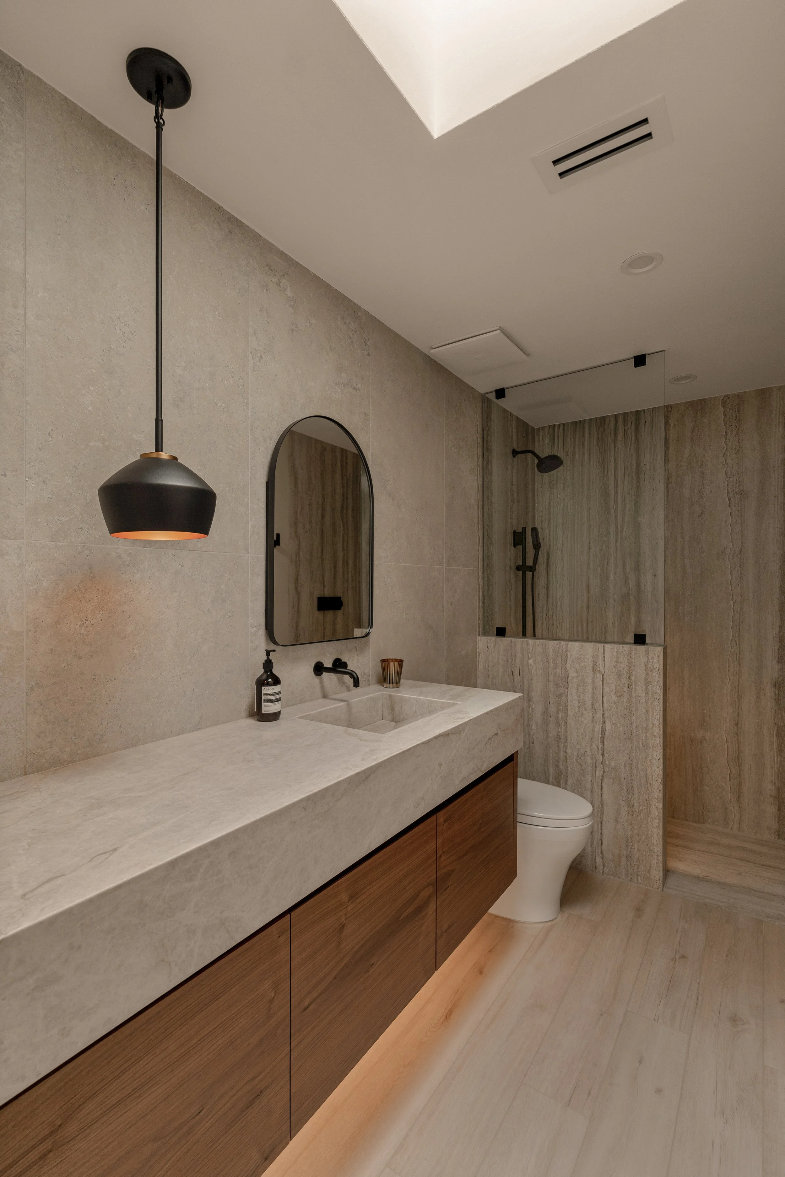 Close-up of the stone vanity, modern mirrors, and ambient wall sconces creating a luxury spa-like feel.