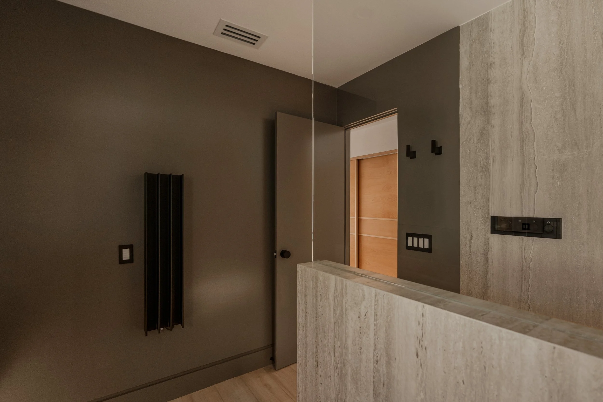 A symmetrical composition capturing the double mirrors, towel warmer, wall sconces, and clean architectural lines.