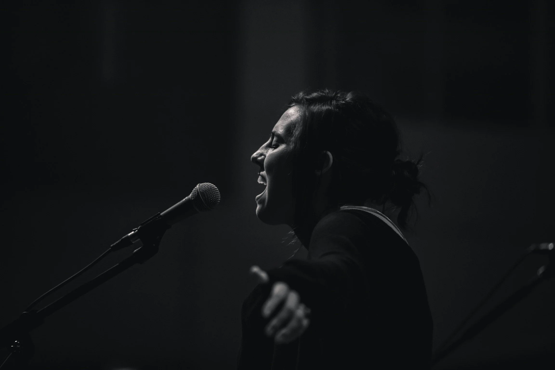 Black and white photo of a person singing into a microphone.