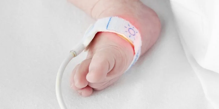 Newborn with pulse oximeter on foot