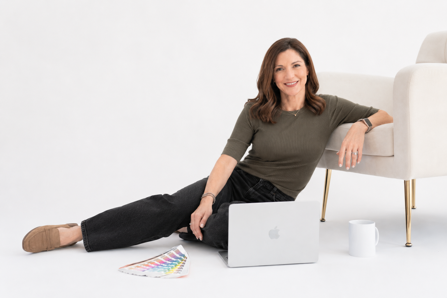 Graphic designer Jill Lawlor seated at her desk with her laptop and design materials.