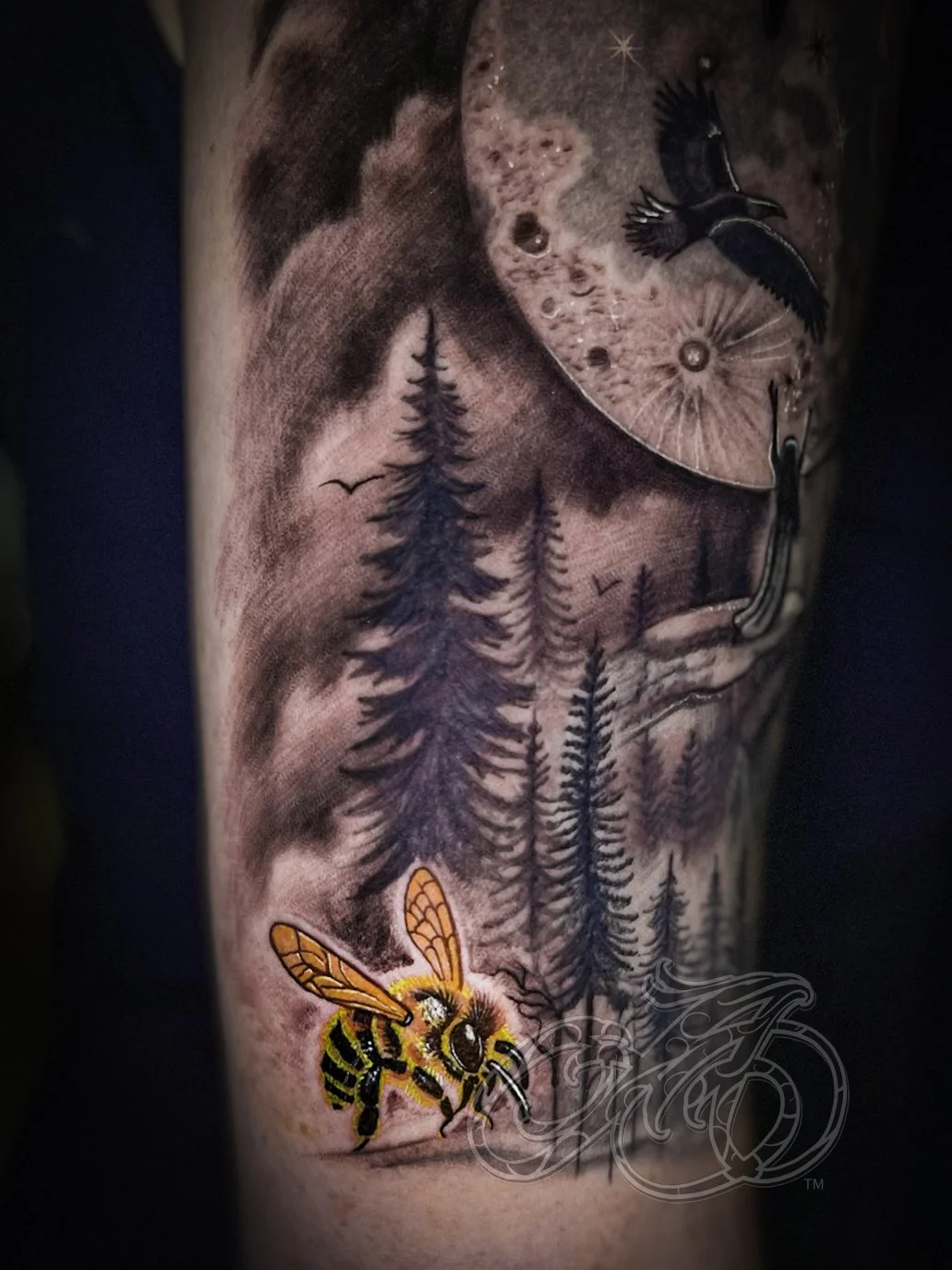 Tattoo of a forest scene with a full moon, a bird flying, and a bee on flowers, depicted in black and gray with a colorful bee.
