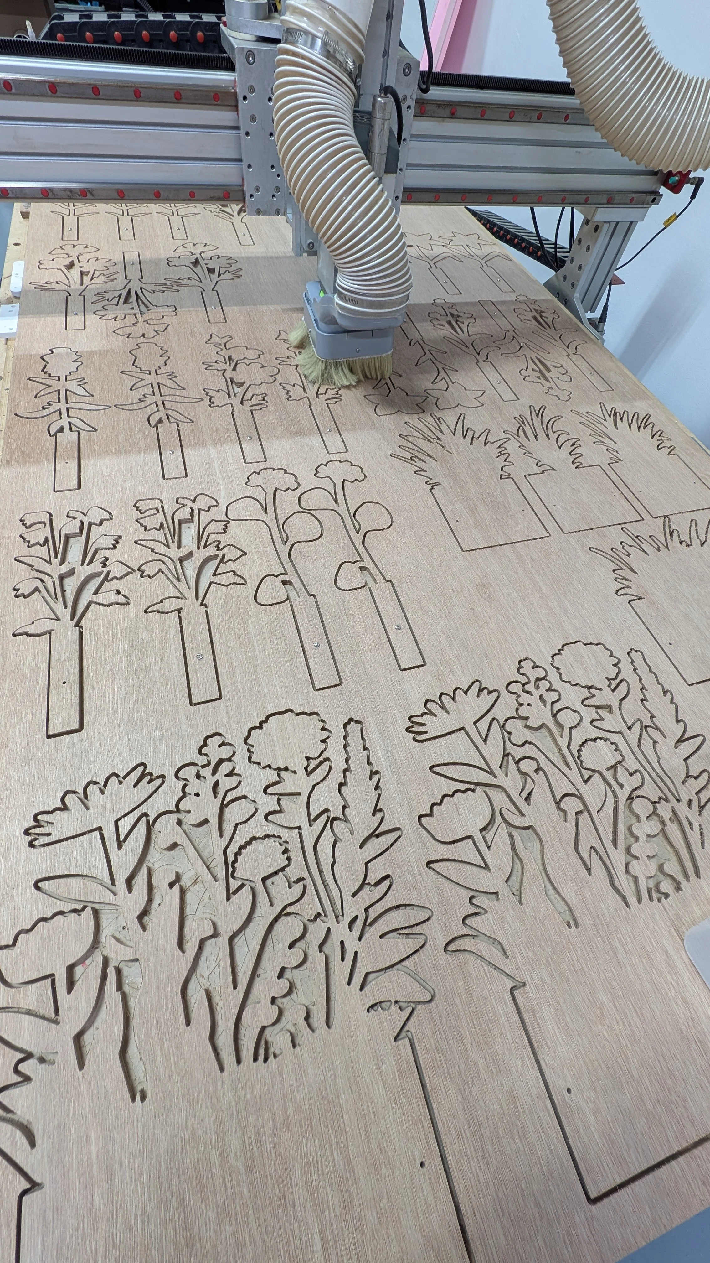Laser cutter carving plant designs into a wooden surface.