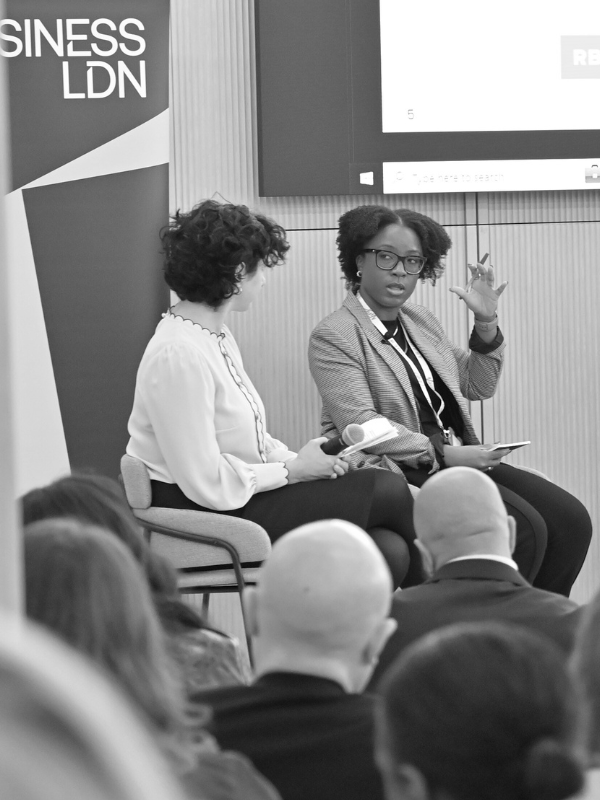 Black and white photo of CBI's Katie Dash speaking on a W&J Summit panel in London 2024 next to RBIJ's Maha Jweied.