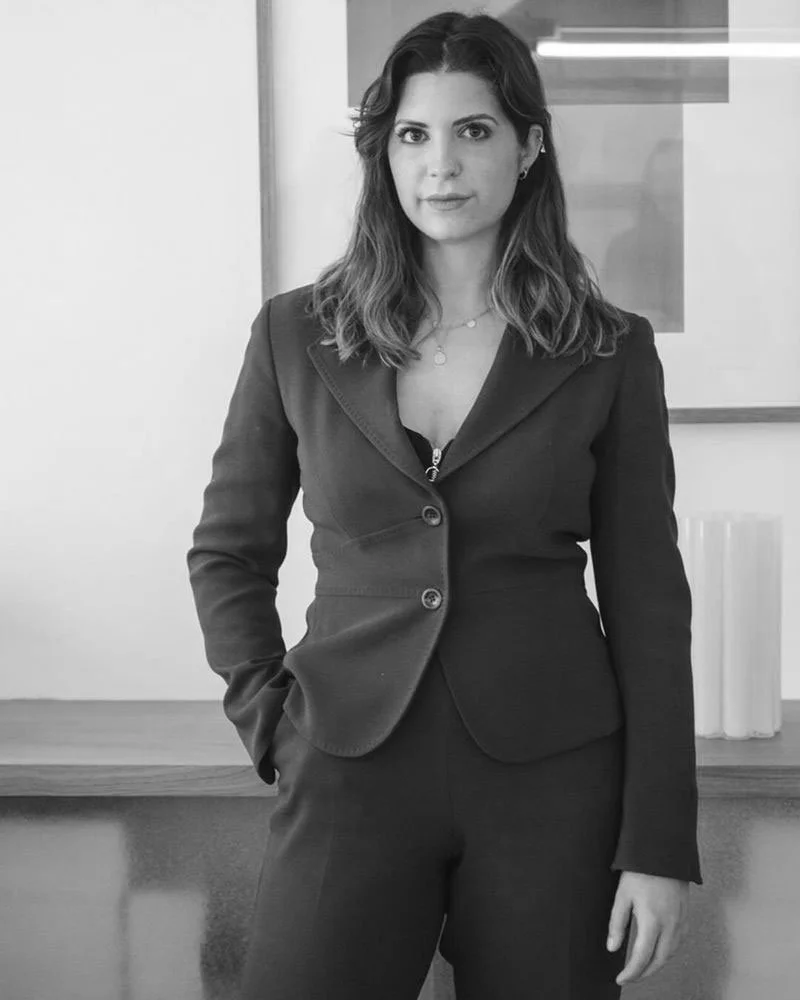 Femme en costume noir devant un mur avec un cadre.