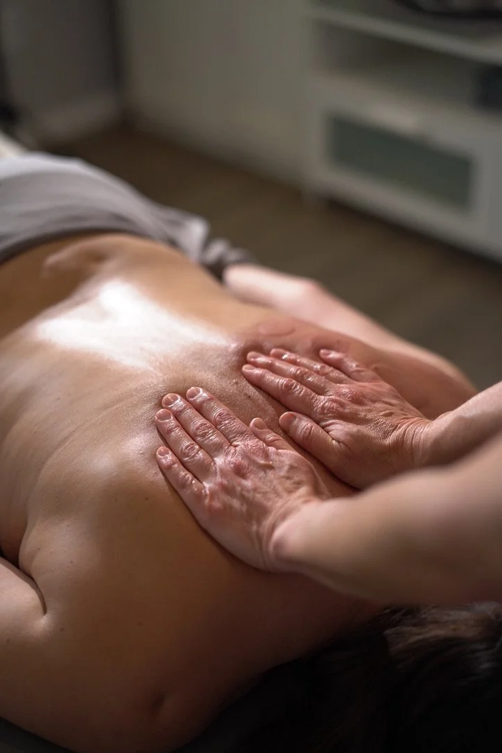 Close-up of a person receiving a massage, focusing on the back being massaged with hands.