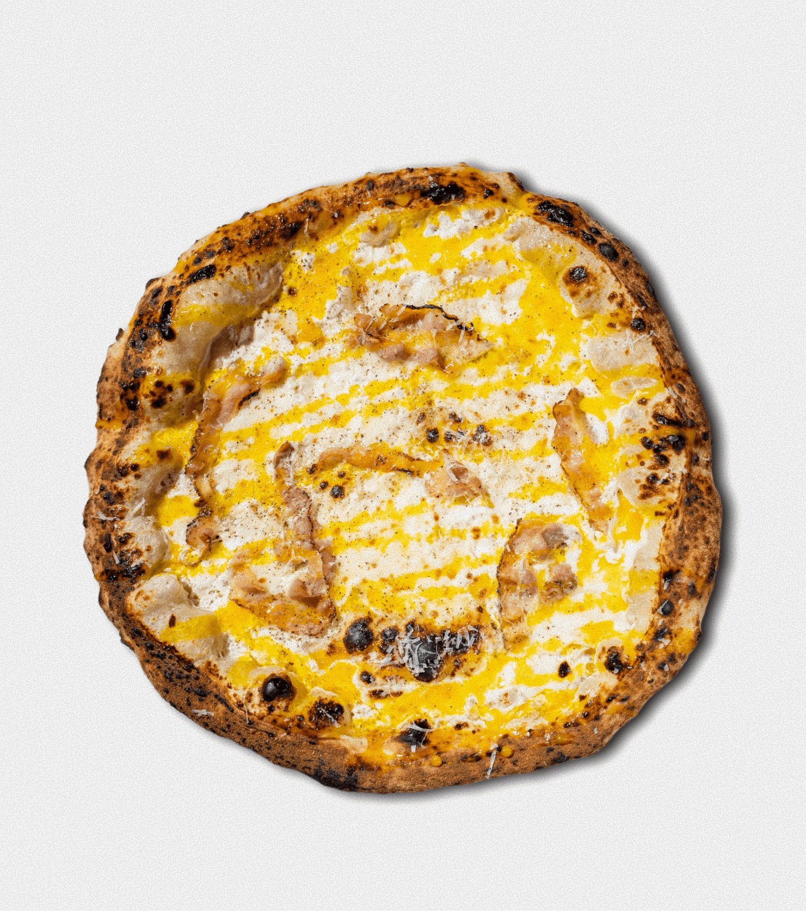 A pizza with cheese, pieces of chicken, and a drizzle of yellow sauce on top, with a slightly charred crust.