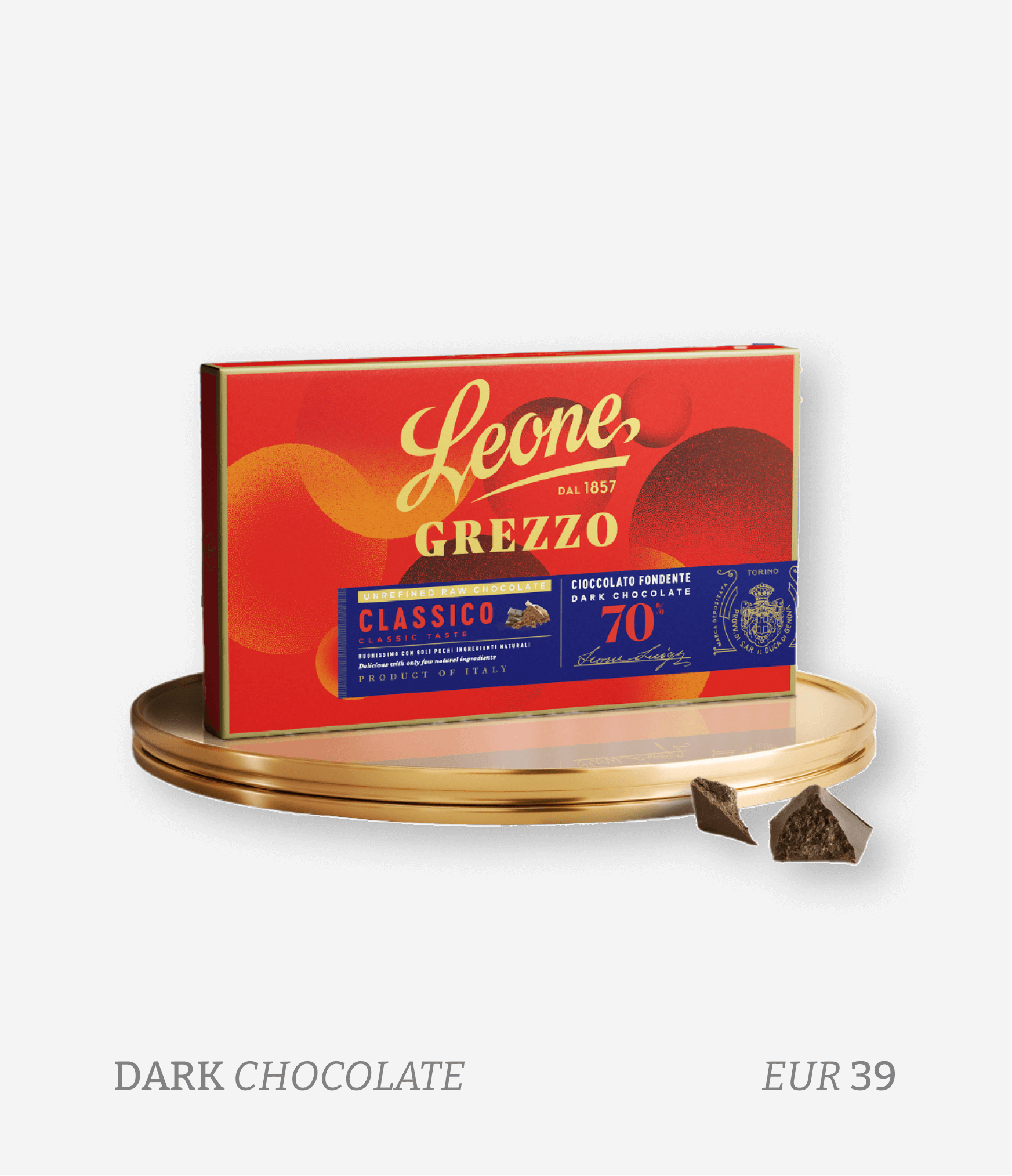 A box of Leone Grezzo dark chocolate placed on a gold tray with two broken pieces of chocolate in front of it. The packaging is red and blue with gold and white text.