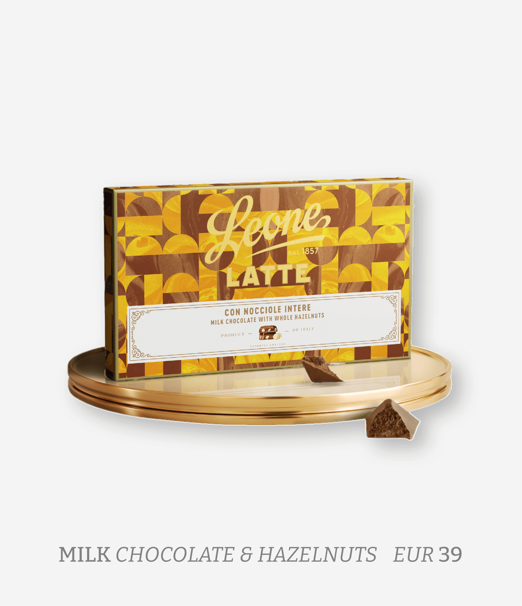 A box of Leone latte milk chocolate with whole hazelnuts, placed on a gold-colored tray with two chocolate pieces in front.