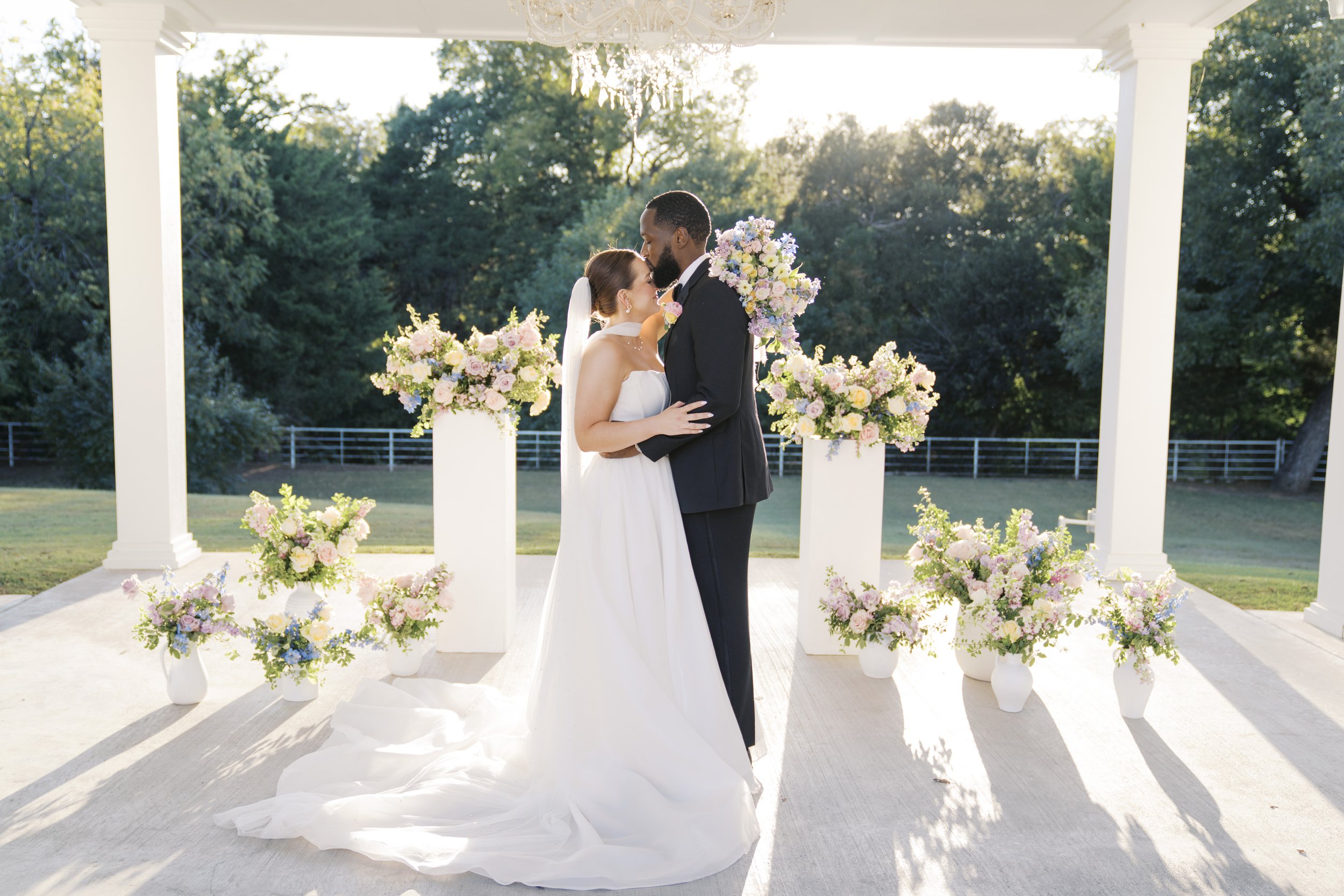 Bride and groom at Romantic outdoor wedding ceremony florals designed by a Dallas luxury wedding planner.