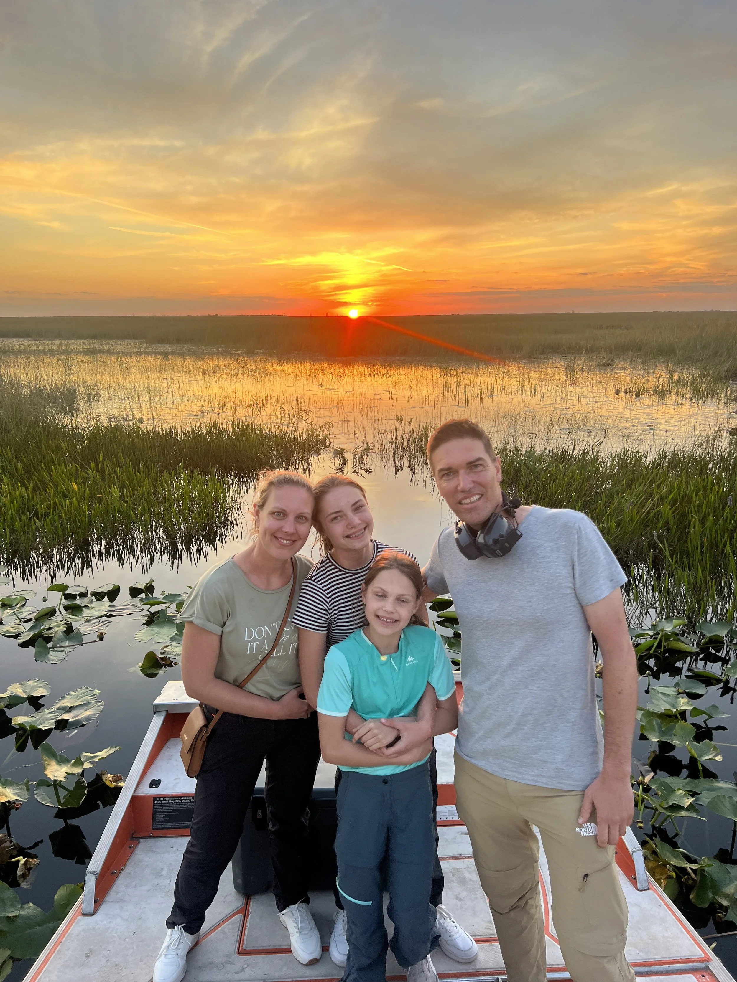 Family aboard an airboat at sunset over the Everglades marsh