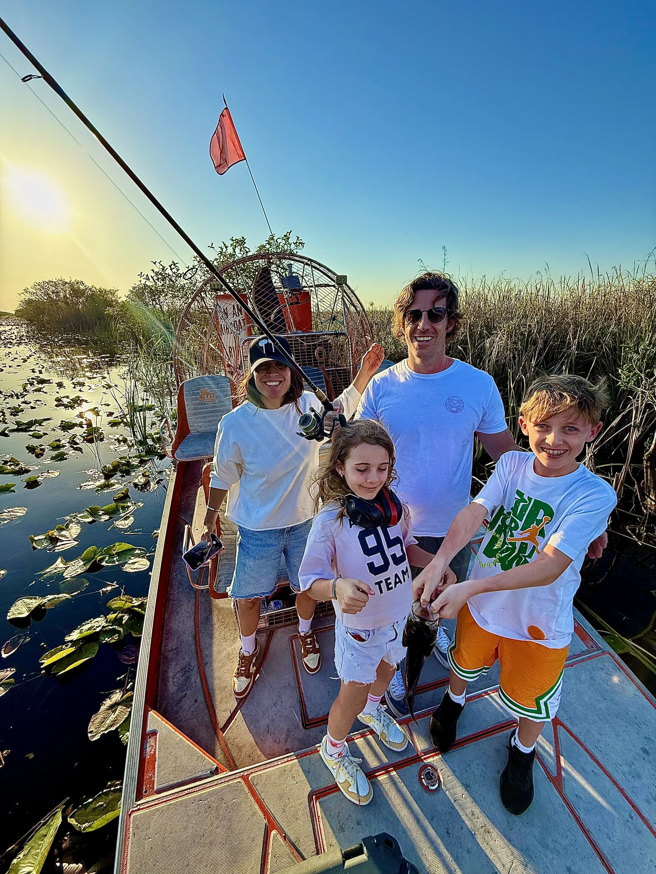 Family displaying a largemouth bass aboard an Everglades airboat