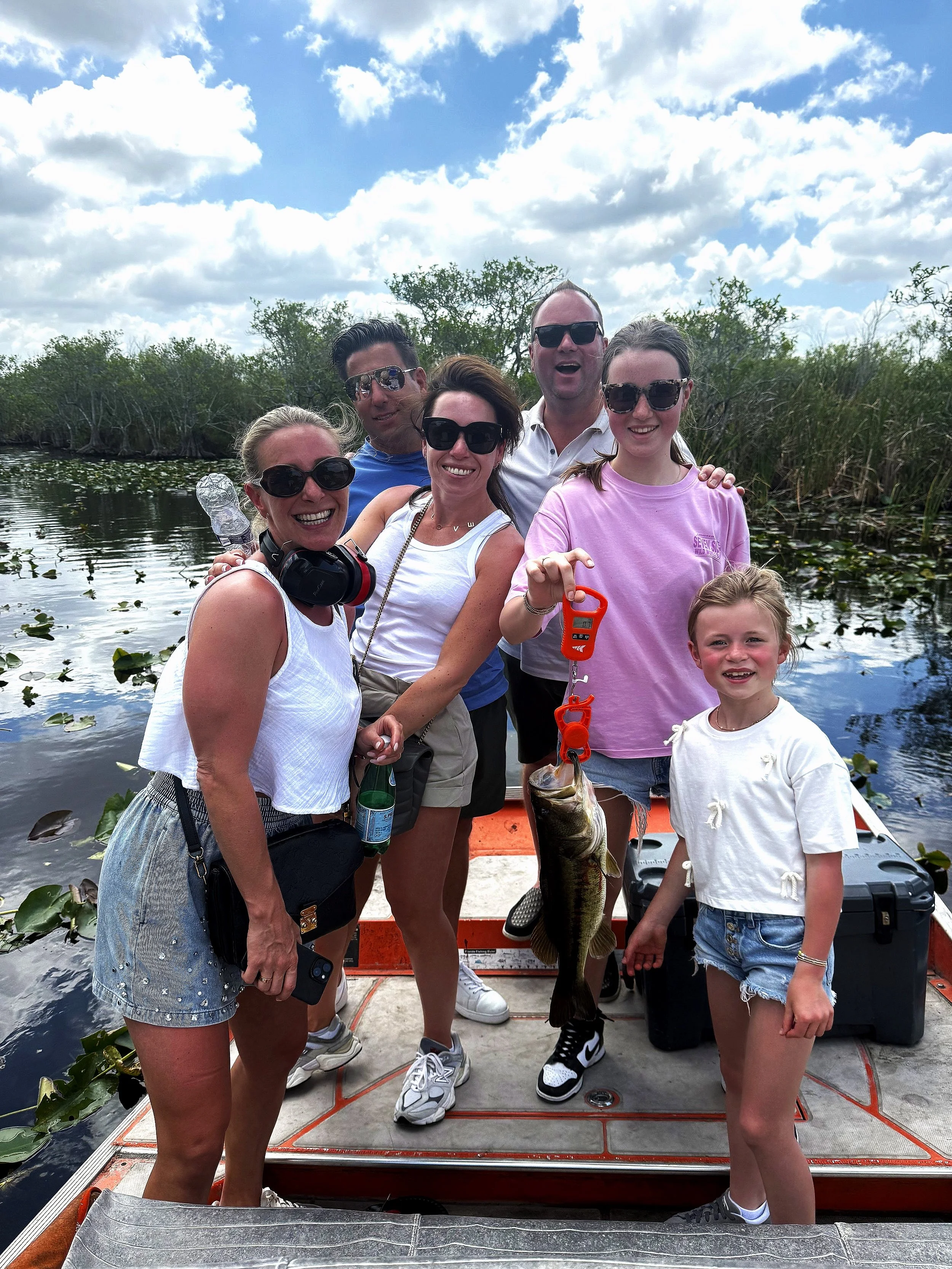 Family displaying their catch aboard an airboat in the Everglades marsh