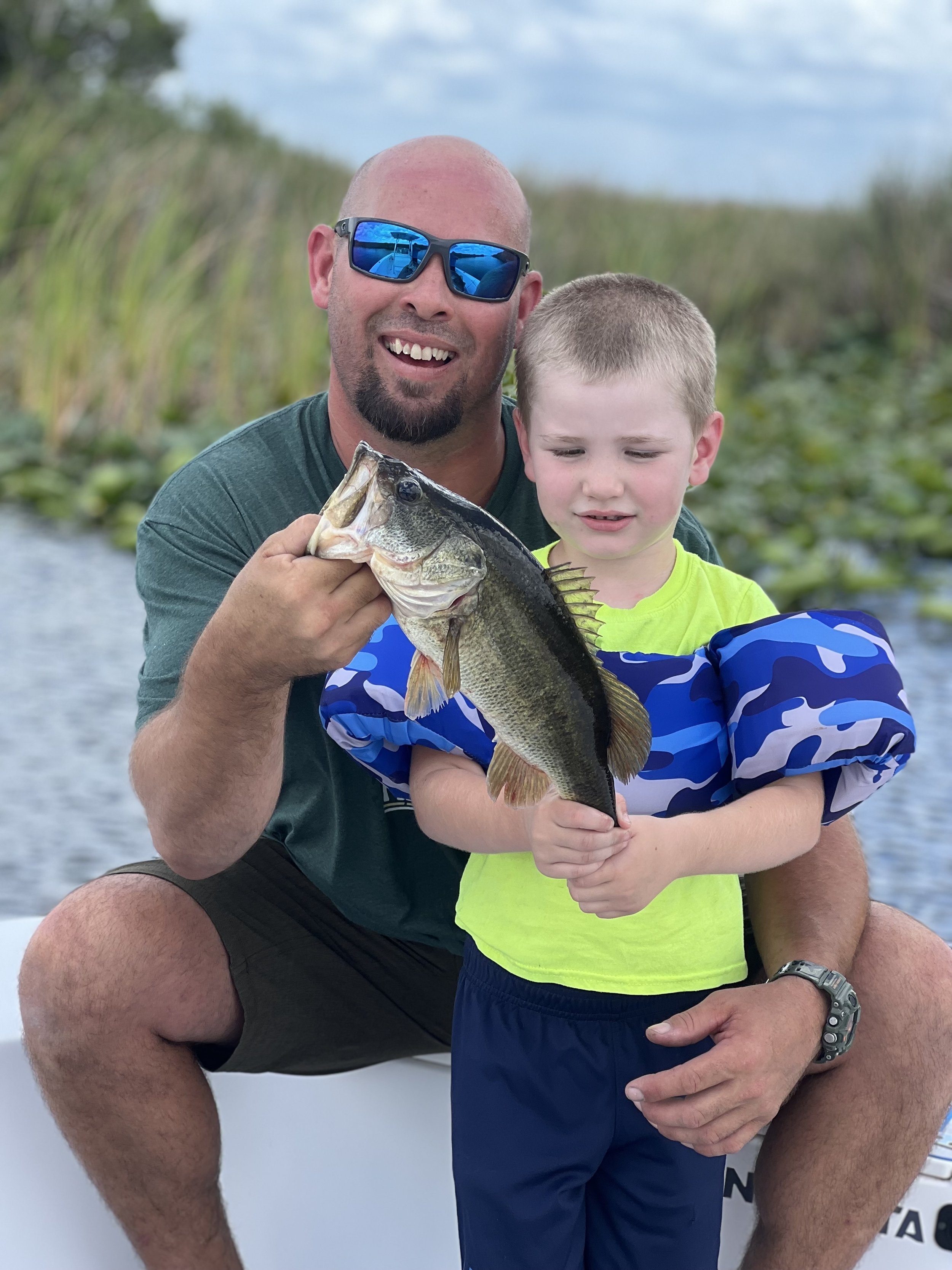 Man and boy holding their fish beside an Everglades waterway