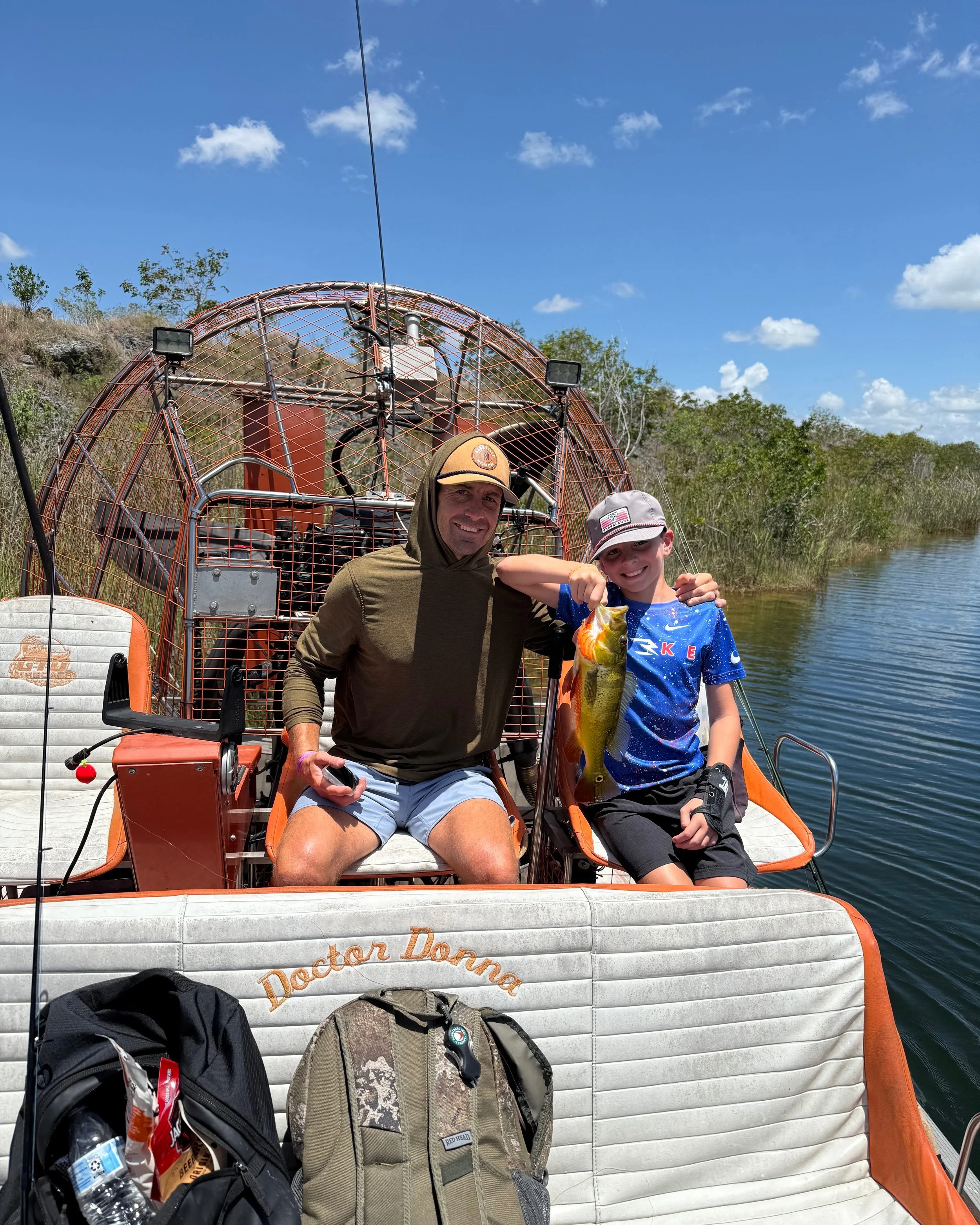 Man and boy holding a peacock bass aboard an Everglades airboat