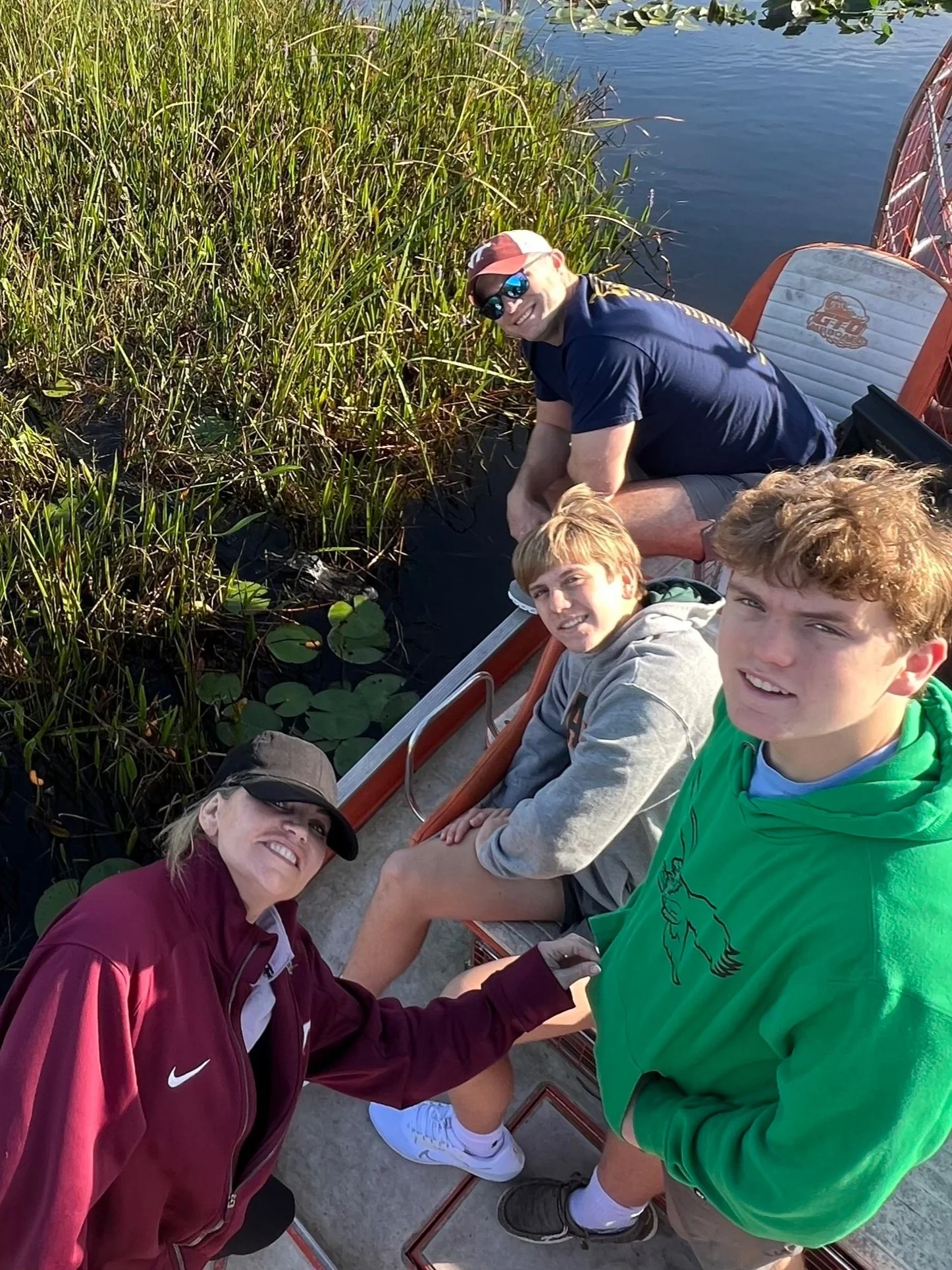 Guests on a private Everglades airboat tour beside an alligator in the marsh
