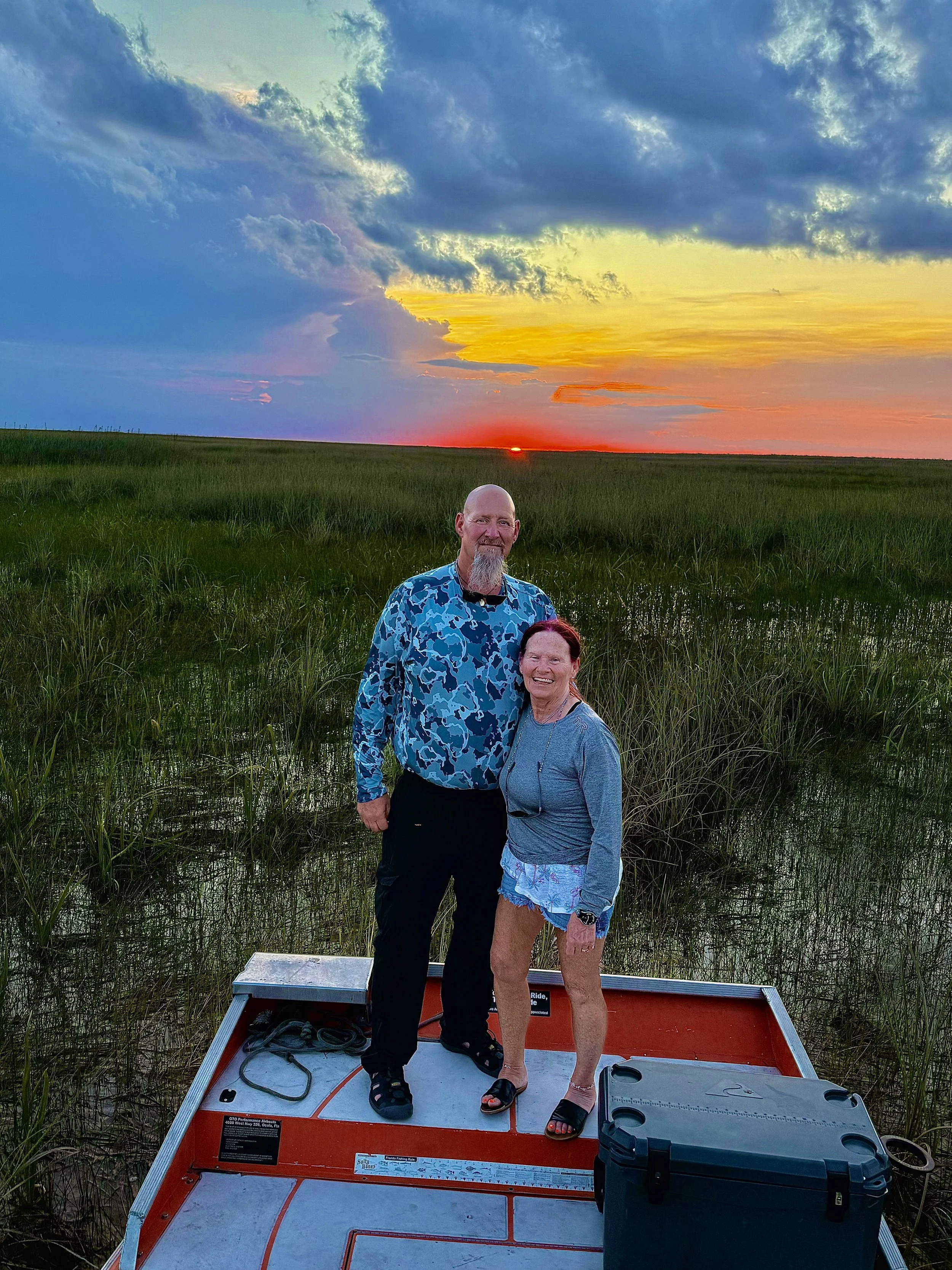 Couple on an airboat at sunset in the Everglades marsh