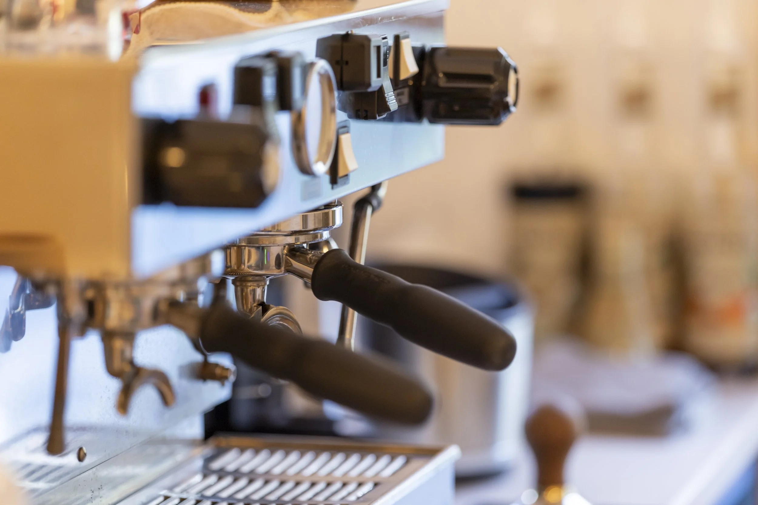 Close-up of a professional espresso machine with black handles in a coffee shop or cafe.