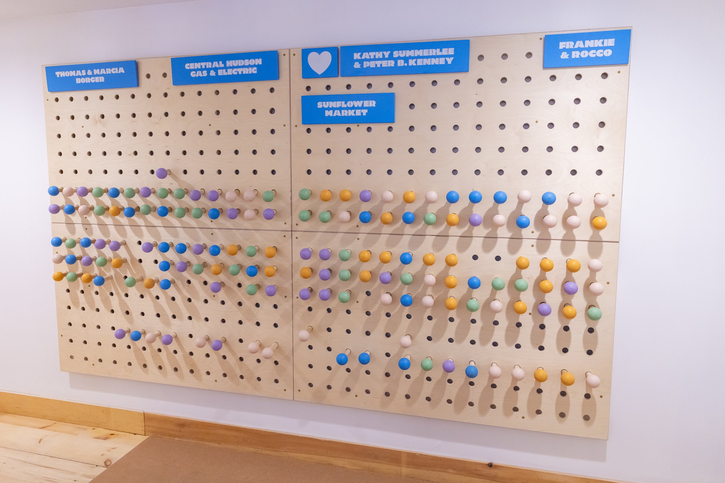 Wooden pegboard with colorful pegs and blue labels for different groups or categories