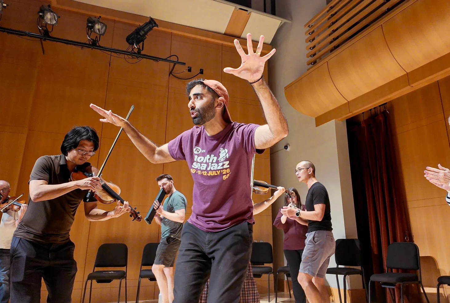 People move around in a circle on a stage, playing instruments or moving to the music.