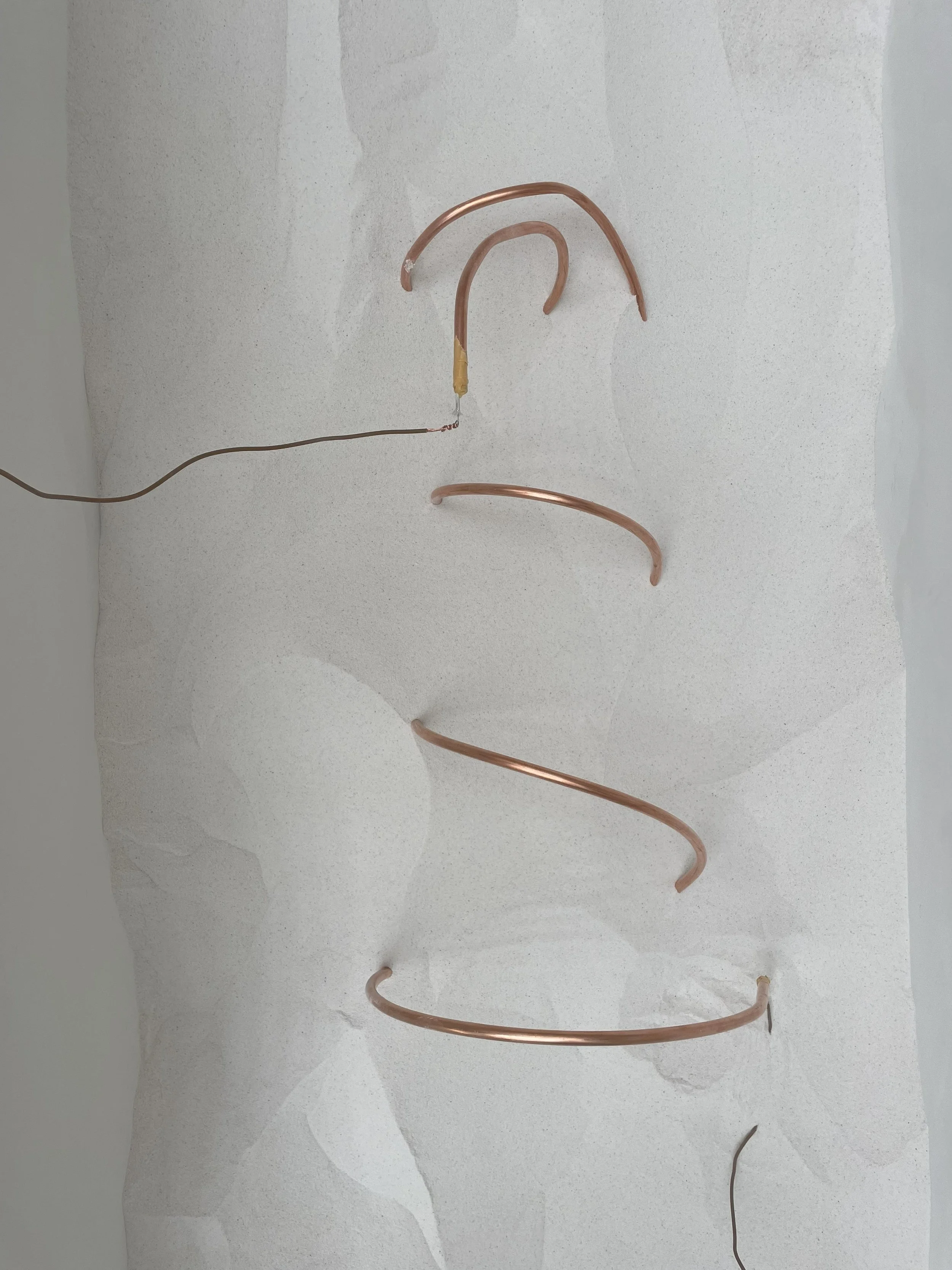 By connecting a hot wire embedded in the copper to the electrical circuit, the surrounding material is gradually heated. This heating causes the material to solidify around the wire, thickening and building up over time.