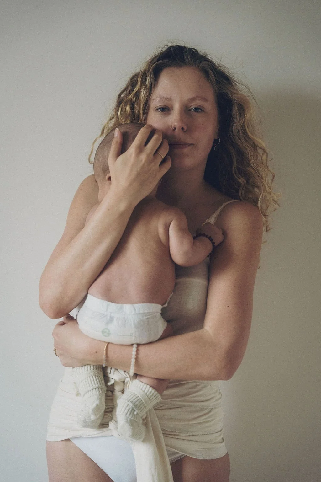 Nieuwe mama met bengkung belly bind en met baby op de arm in haar postpartum periode