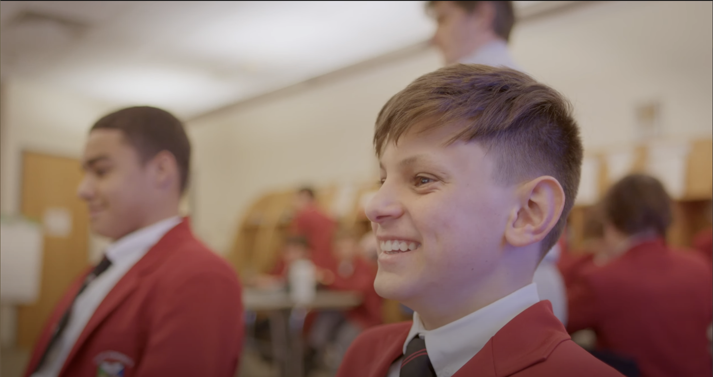 Students in school uniforms smiling and sitting in classroom.