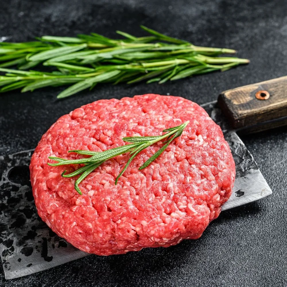 Raw ground beef burger patty with fresh rosemary from Dry Creek Pastures beef shares