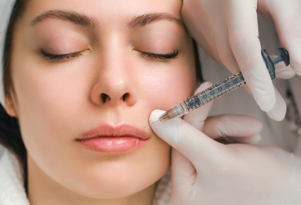 Woman receiving a cosmetic injection in her lips from a medical professional. Woman receiving filler injection into her lips.