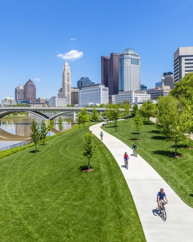 Winding bike paths, columbus downtown skyline pictured in background, and lush green surrounding at Scioto Mile