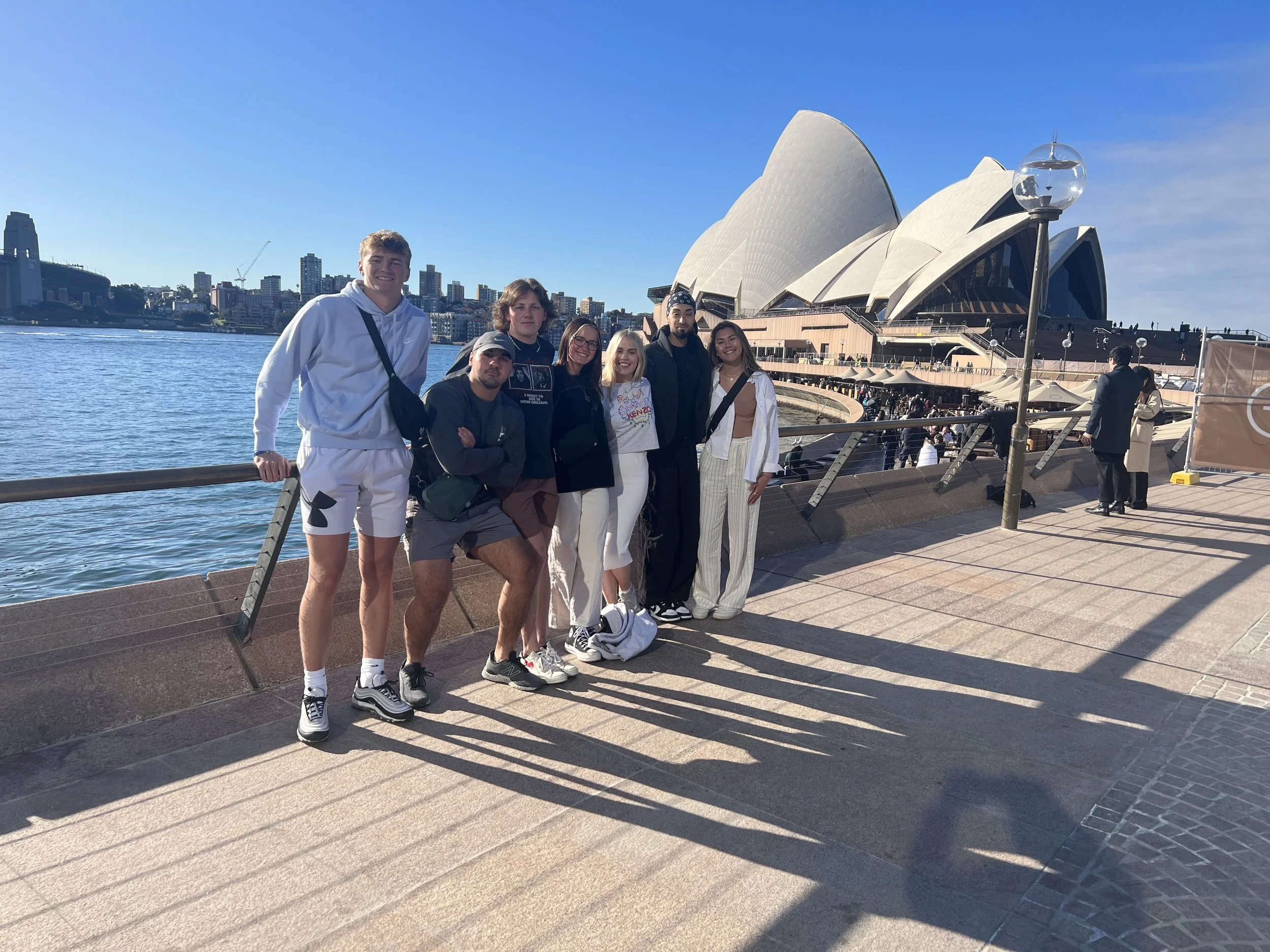 a group of Chloe Pennoni's friends at the syndey opera house, with the harbor in the background