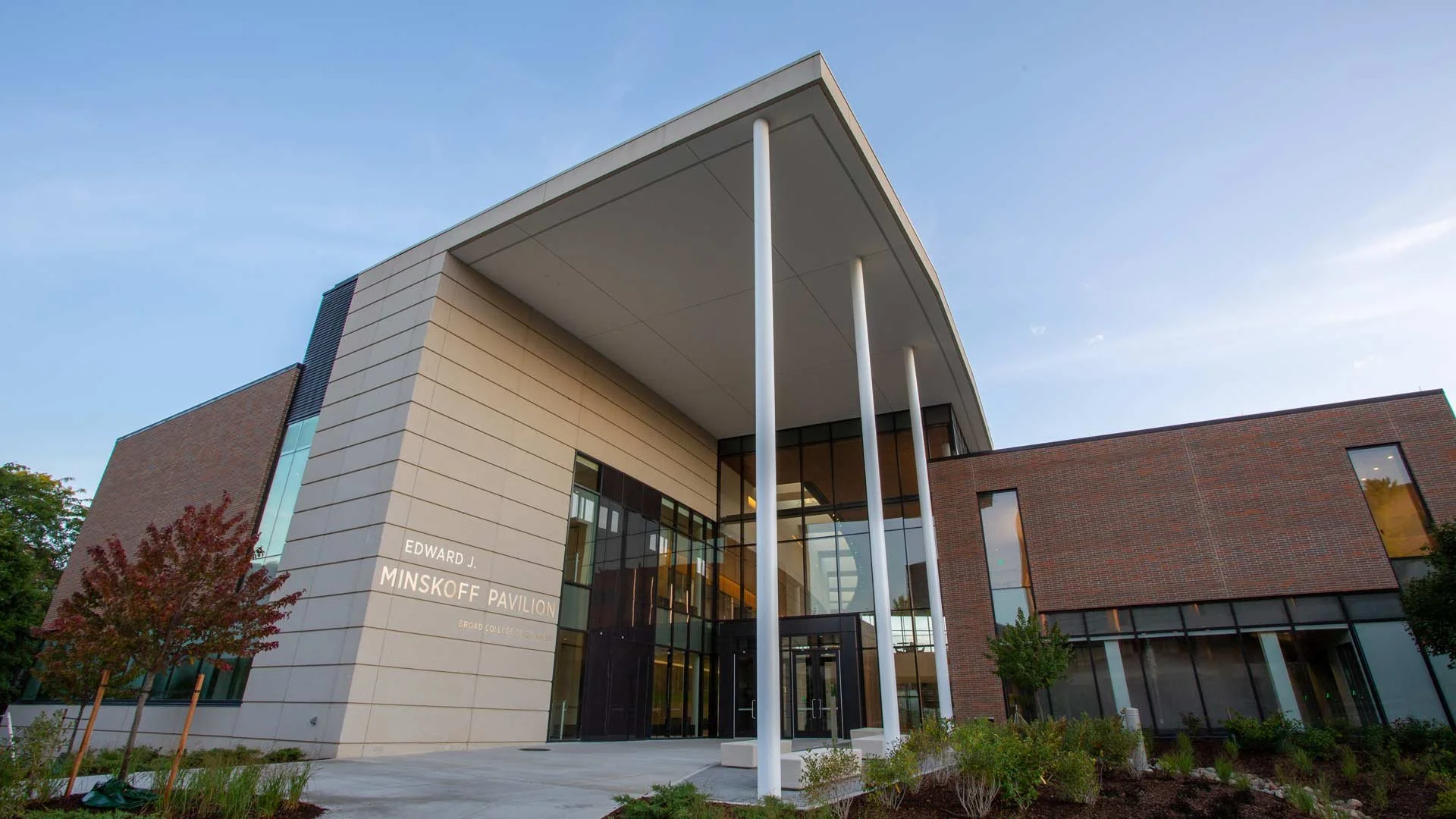 Image of the Minskoff Pavilion, a modern architectural structure featuring a sleek design with large glass windows, surrounded by landscaped greenery and pathways.