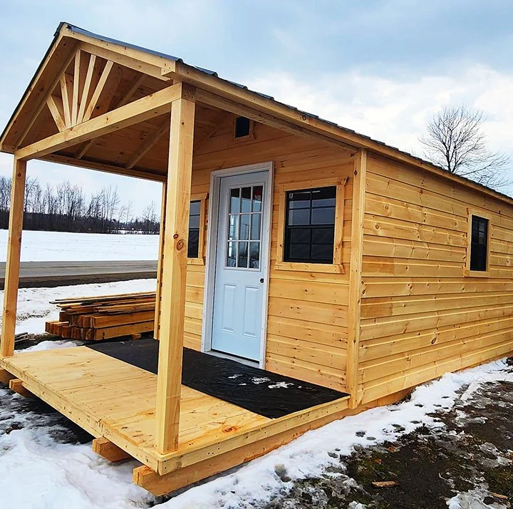 Cabanon Outaouais, Cabanons Outouais. Petite maison en bois avec porche, située dans un paysage enneigé, construction en cours. Cabanon. Backyard Shed. Remise. Cabanons.