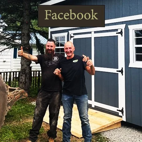 Cabanons nature, cabanon Outaouais. Deux hommes souriants posant devant un panneau Facebook, l'un faisant un signe de pouce en l'air. À l'arrière, une maison en bois est visible.