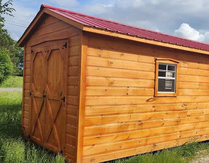 Cabanons nature, cabanon Outaouais. Petite cabane en bois avec un toit en métal rouge, une fenêtre et des portes doubles en bois, située dans un espace vert. Cabanon. Backyard Shed. Remise. Cabanons.